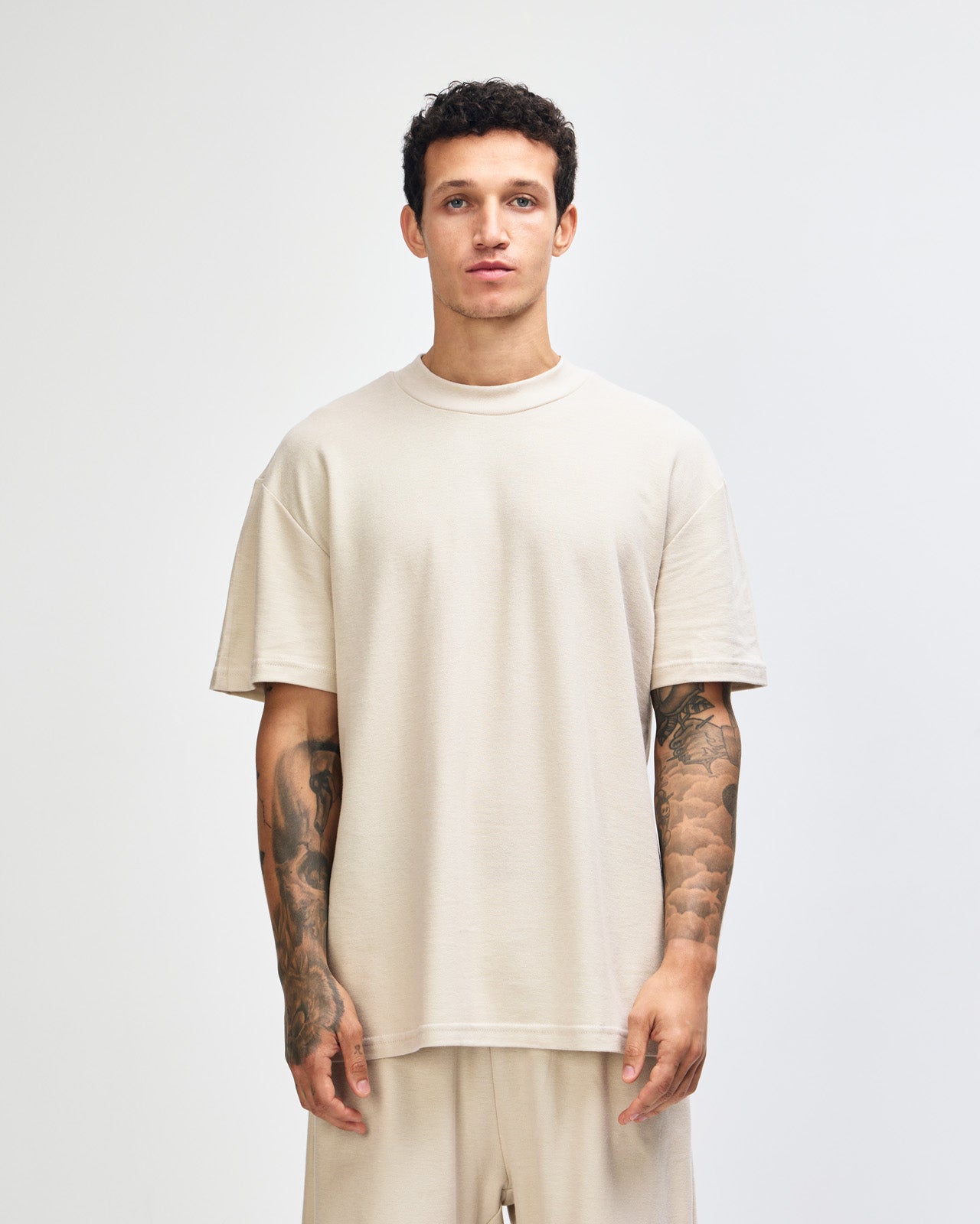 Male model wearing a Pique Unisex Mockneck Tee (front pose) -bone