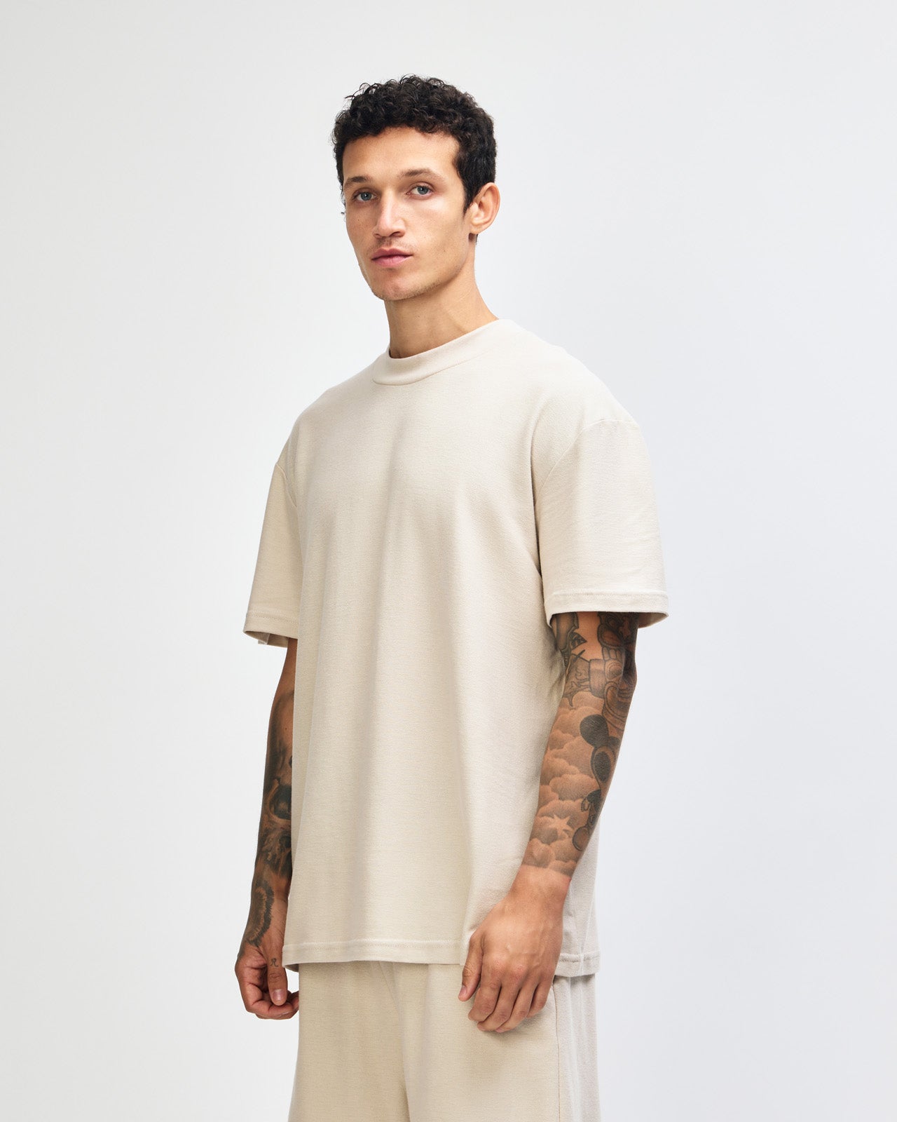 Male model wearing a Pique Unisex Mockneck Tee (front pose) -bone
