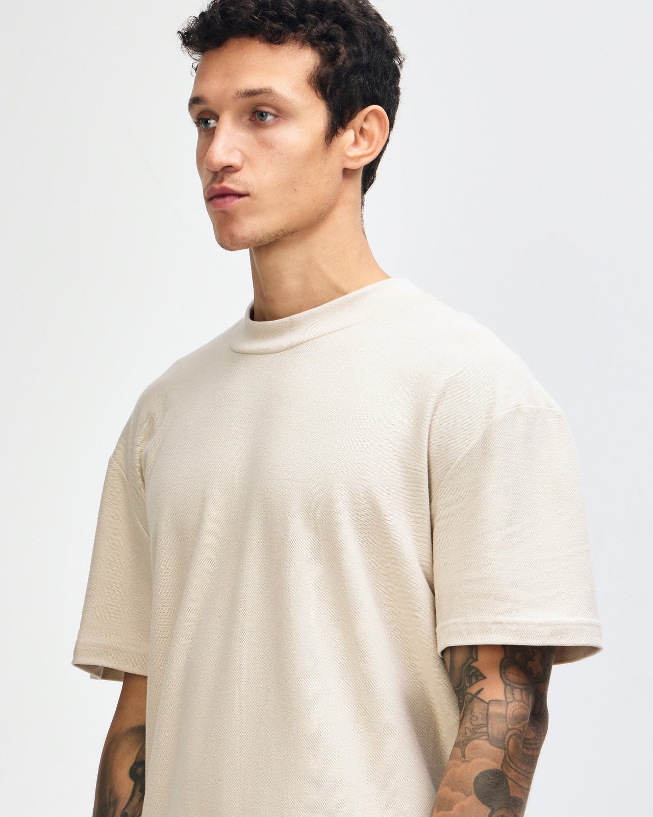 Male model wearing a Pique Unisex Mockneck Tee (front pose) -bone