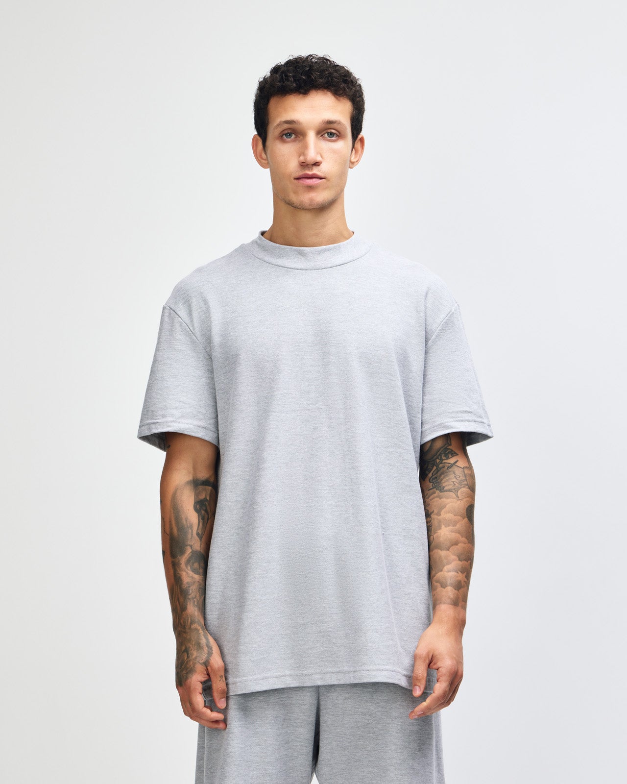 Male model wearing a Pique Unisex Mockneck Tee (front pose) -heather grey