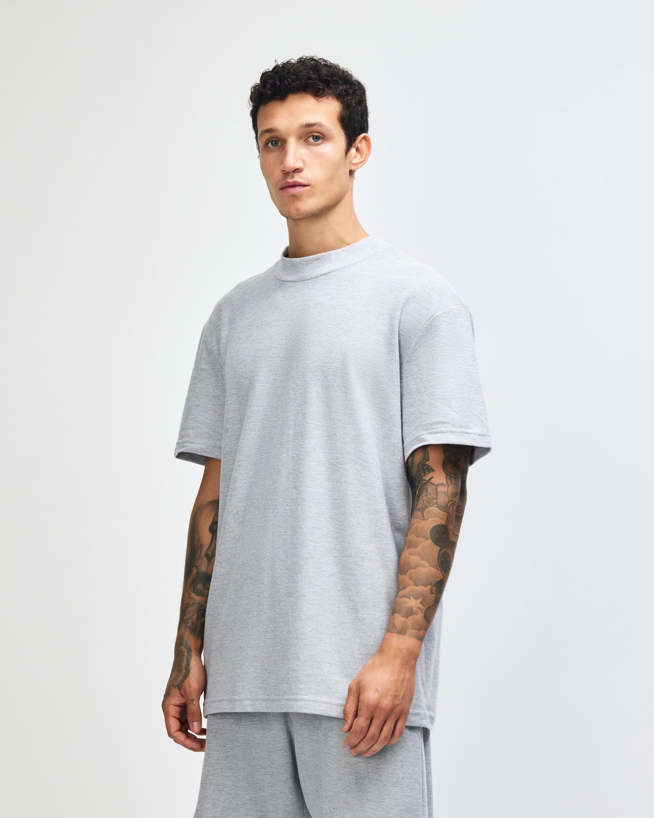 Male model wearing a Pique Unisex Mockneck Tee (front pose) -heather grey