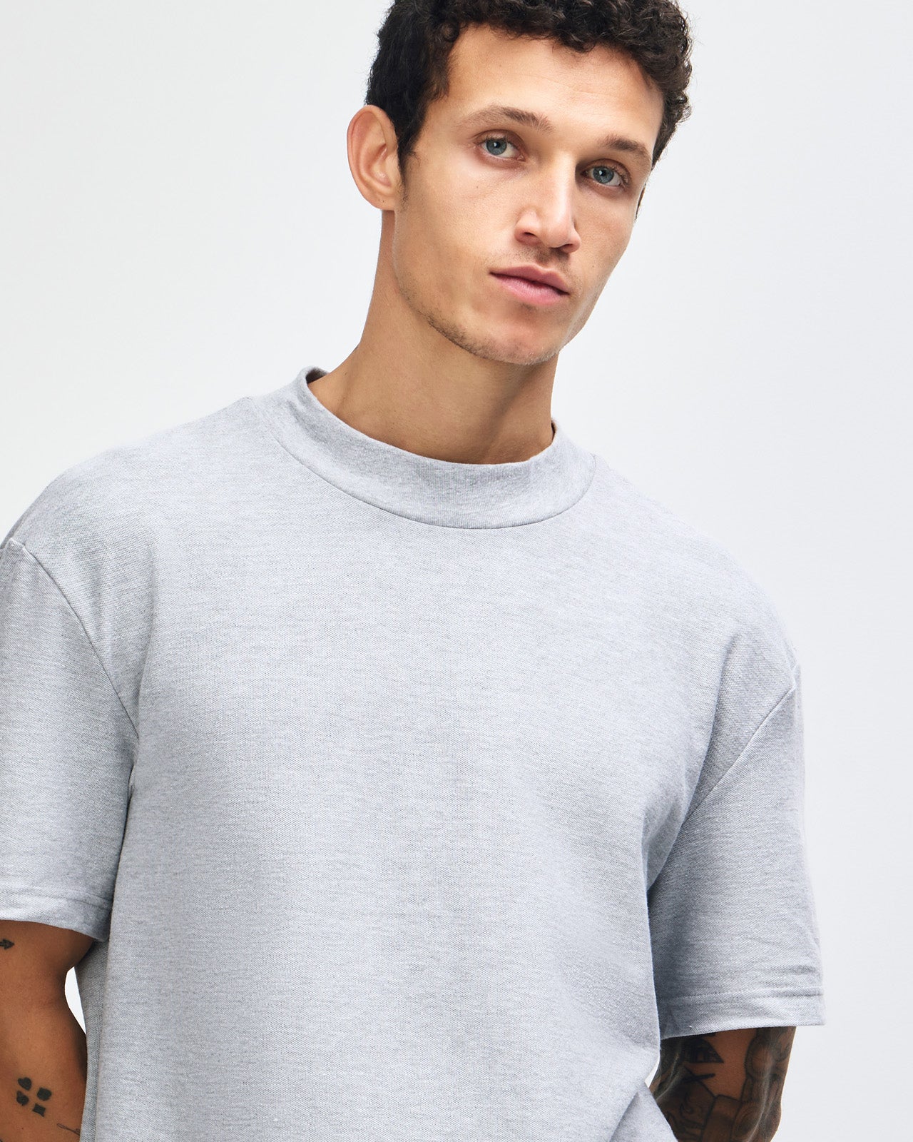 Male model wearing a Pique Unisex Mockneck Tee (front pose) -heather grey