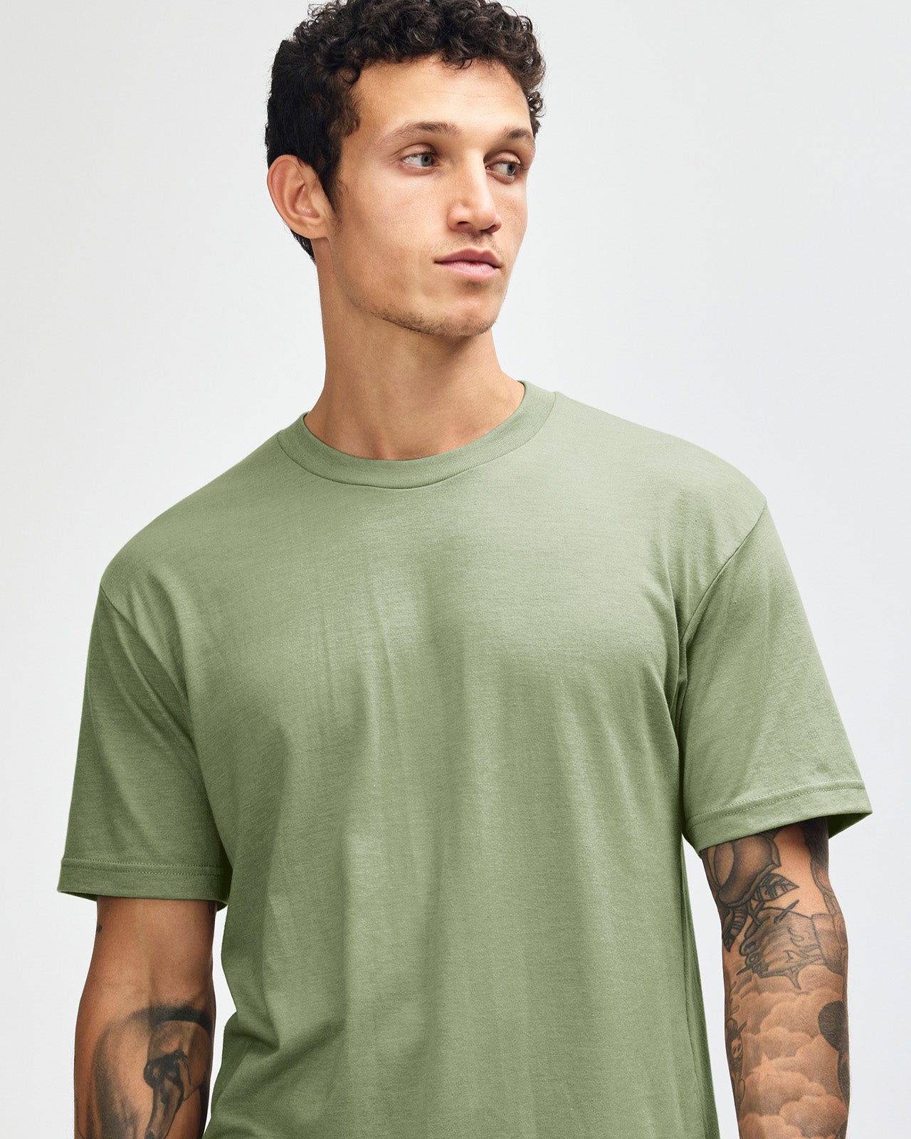 Male model wearing heather sage colour CVC Unisex Short Sleeve Crew Neck Tee (front pose) -heather sage