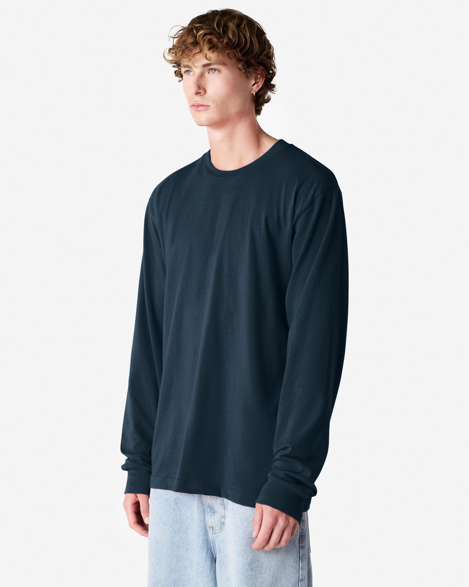 male model wearing American Apparel Navy Colour Fine Jersey Unisex Long Sleeve Crew Neck Tee (half Front pose) -Navy
