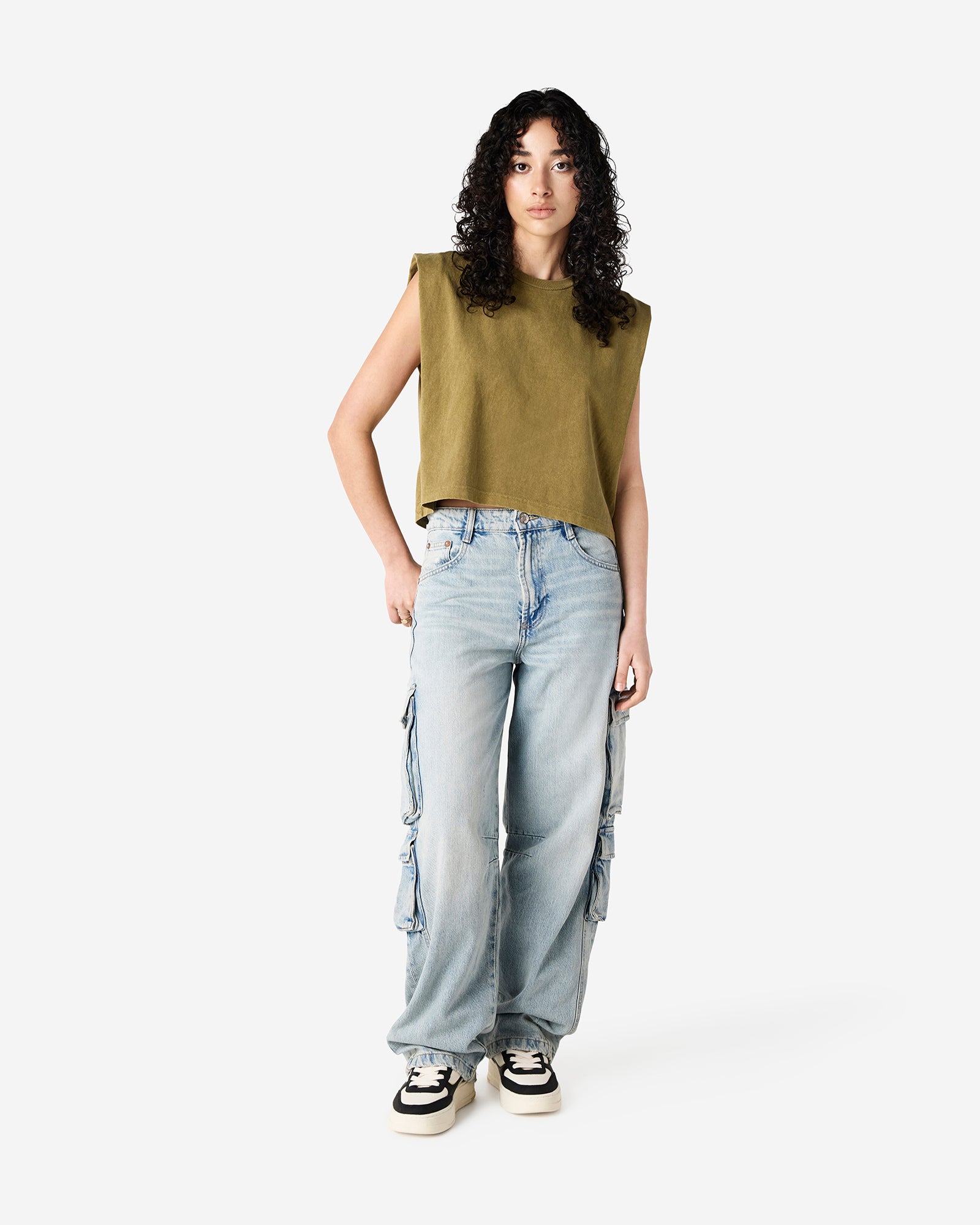 Model wearing a faded army Garment Dyed Women's Muscle Tee, sleeveless, paired with light blue jeans, standing against a plain white background (front pose) -army