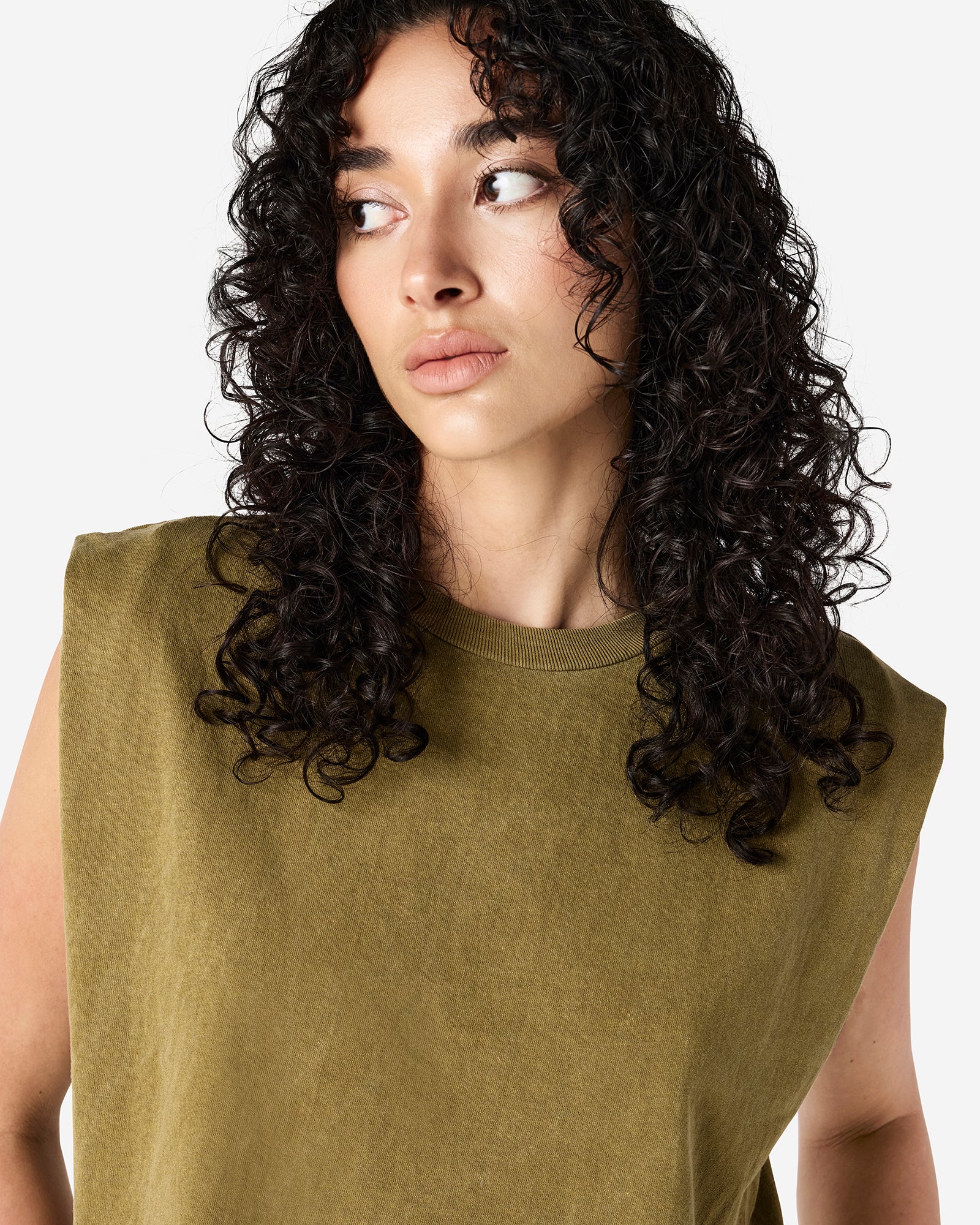 Model wearing a faded army Garment Dyed Women's Muscle Tee, sleeveless, paired with light blue jeans, standing against a plain white background (front pose) -army