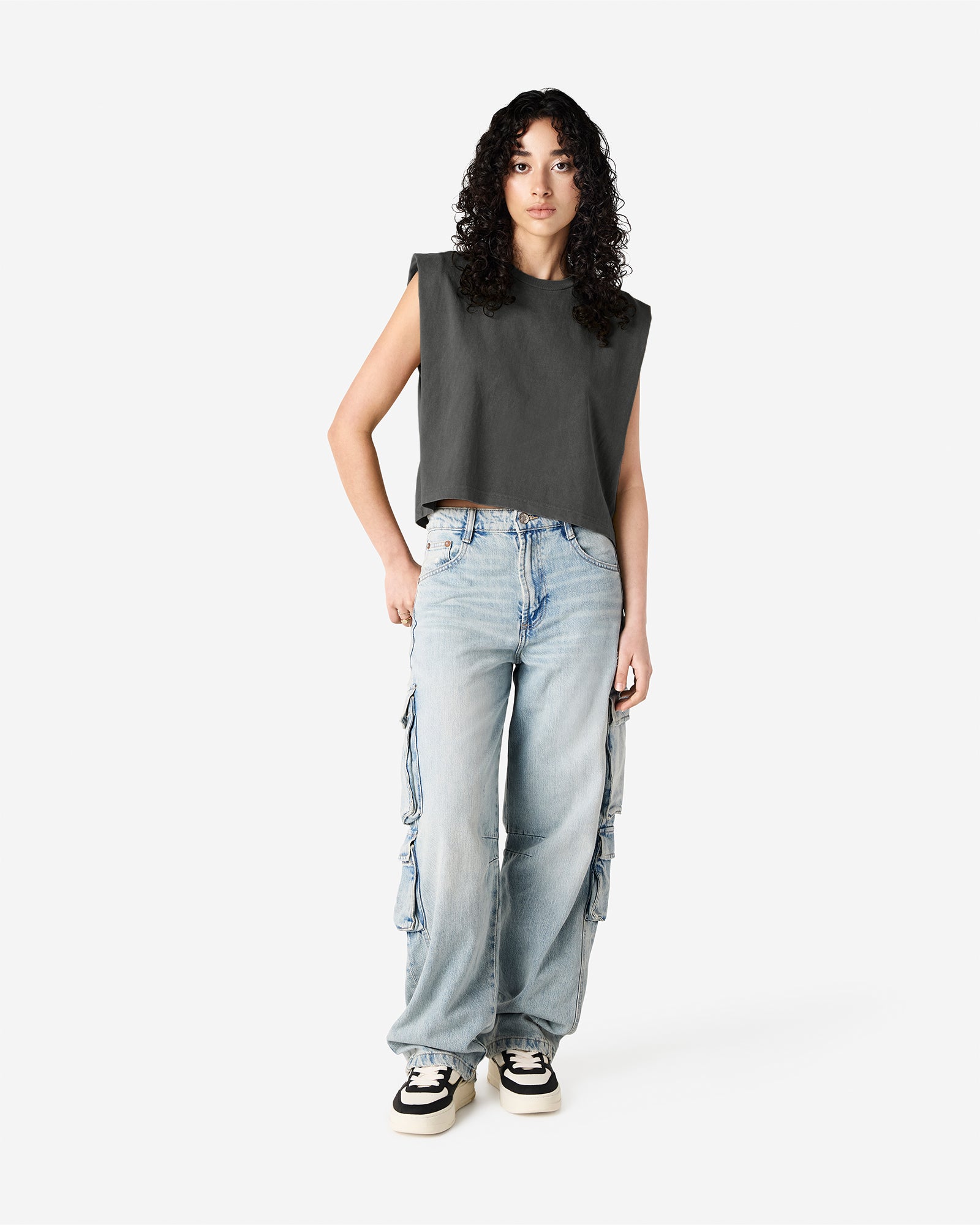 Model wearing a faded black Garment Dyed Women's Muscle Tee, sleeveless, paired with light blue jeans, standing against a plain white background (front pose) -black