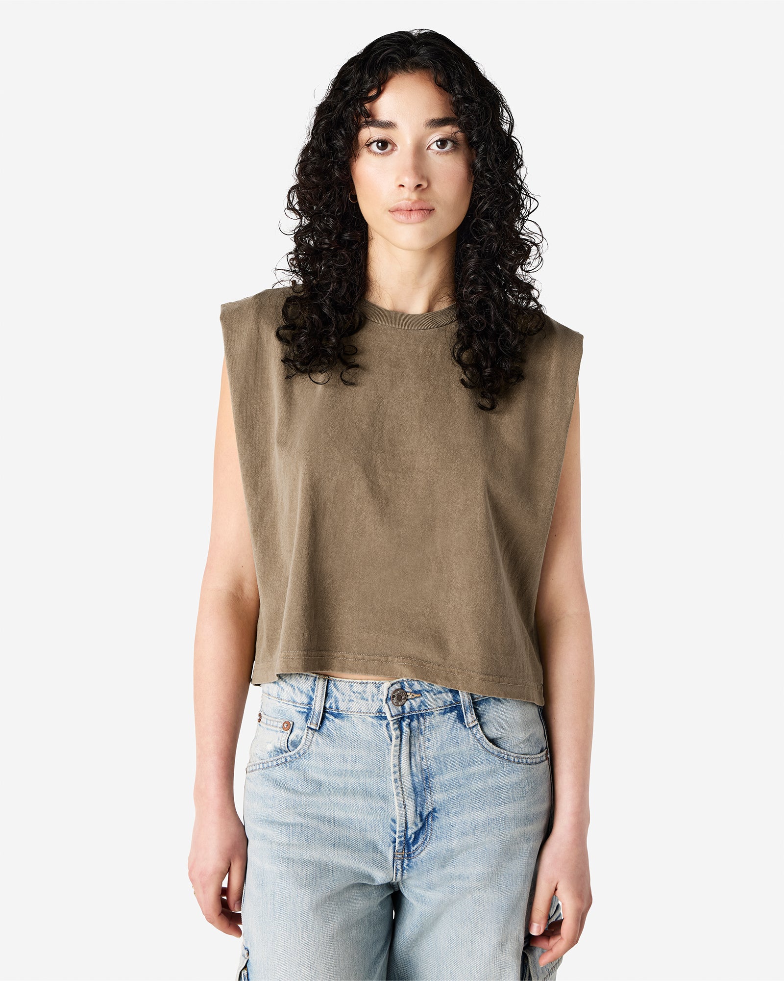 Model wearing a faded brown Garment Dyed Women's Muscle Tee, sleeveless, paired with light blue jeans, standing against a plain white background (front pose) -brown