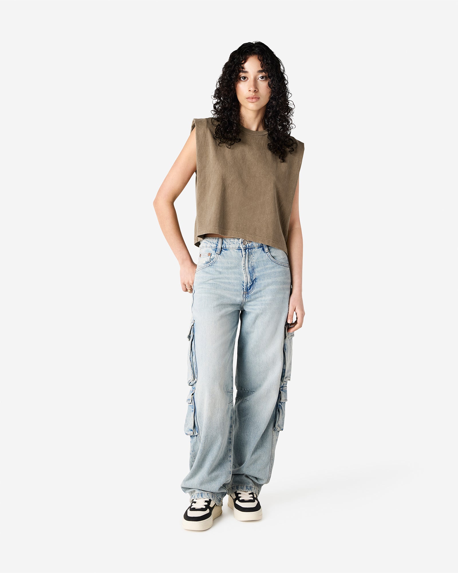 Model wearing a faded brown Garment Dyed Women's Muscle Tee, sleeveless, paired with light blue jeans, standing against a plain white background (front pose) -brown