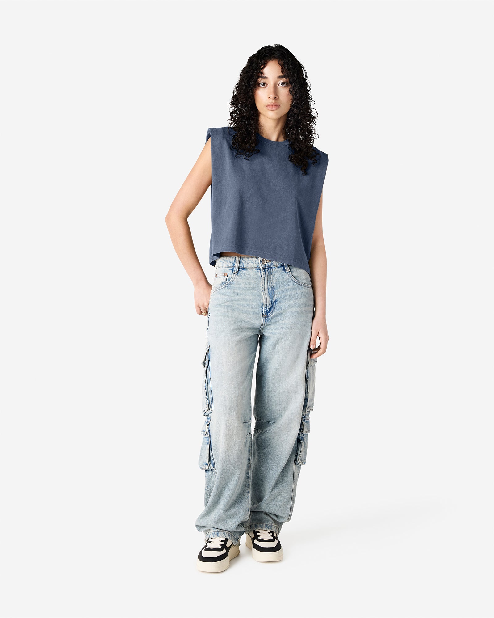 Model wearing a faded navy Garment Dyed Women's Muscle Tee, sleeveless, paired with light blue jeans, standing against a plain white background (front pose) -navy