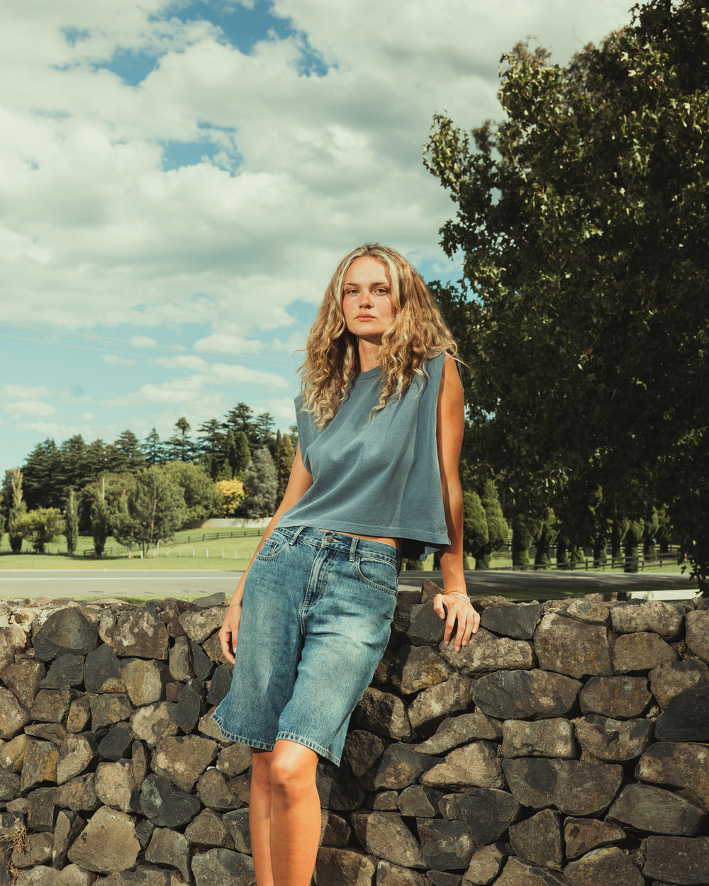 image of Women's Muscle T-Shirt : Model wearing a faded navy Garment Dyed Women's Muscle Tee, sleeveless, paired with light blue jeans, standing against a plain white background (front pose) -navy
