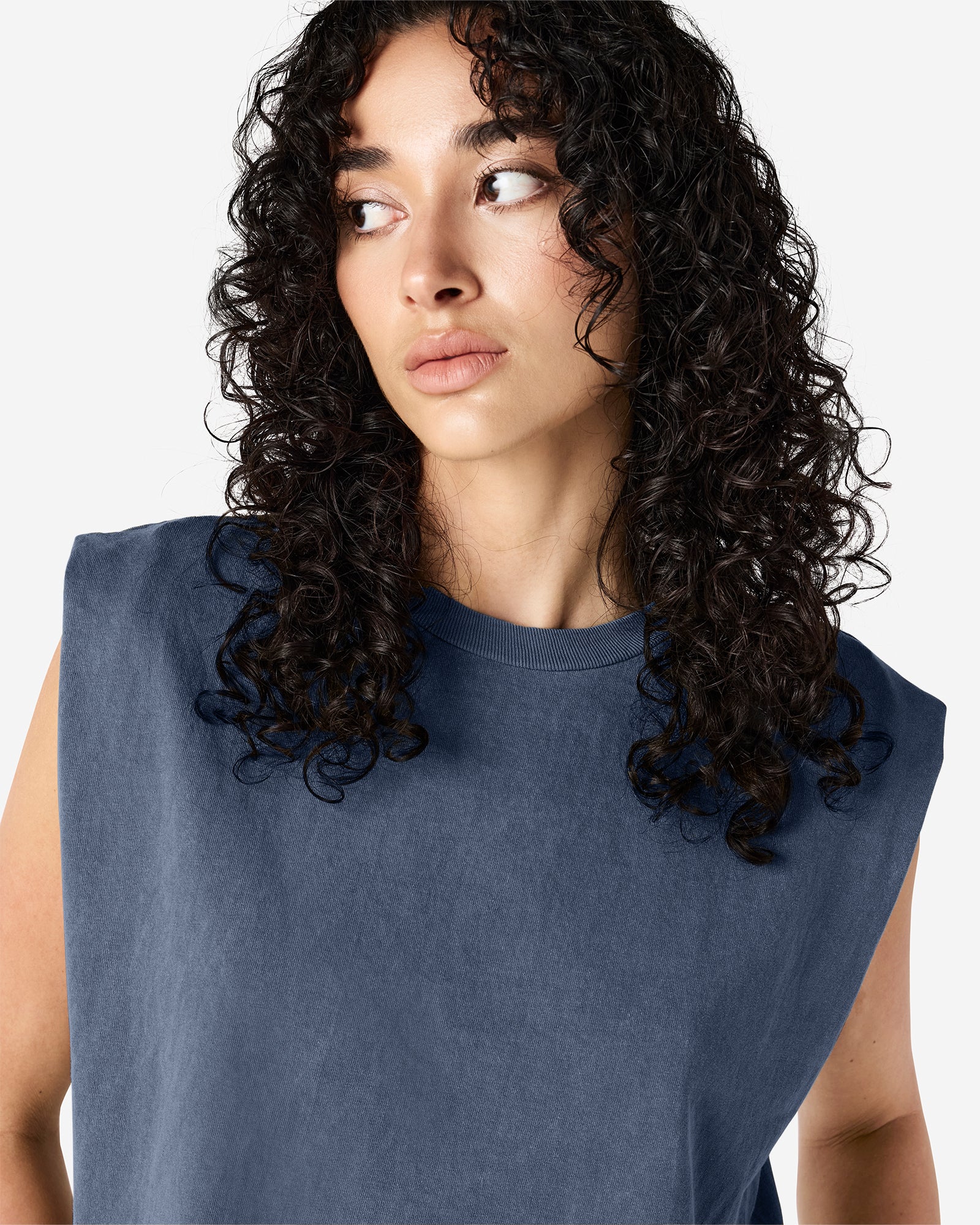 Model wearing a faded navy Garment Dyed Women's Muscle Tee, sleeveless, paired with light blue jeans, standing against a plain white background (front pose) -navy