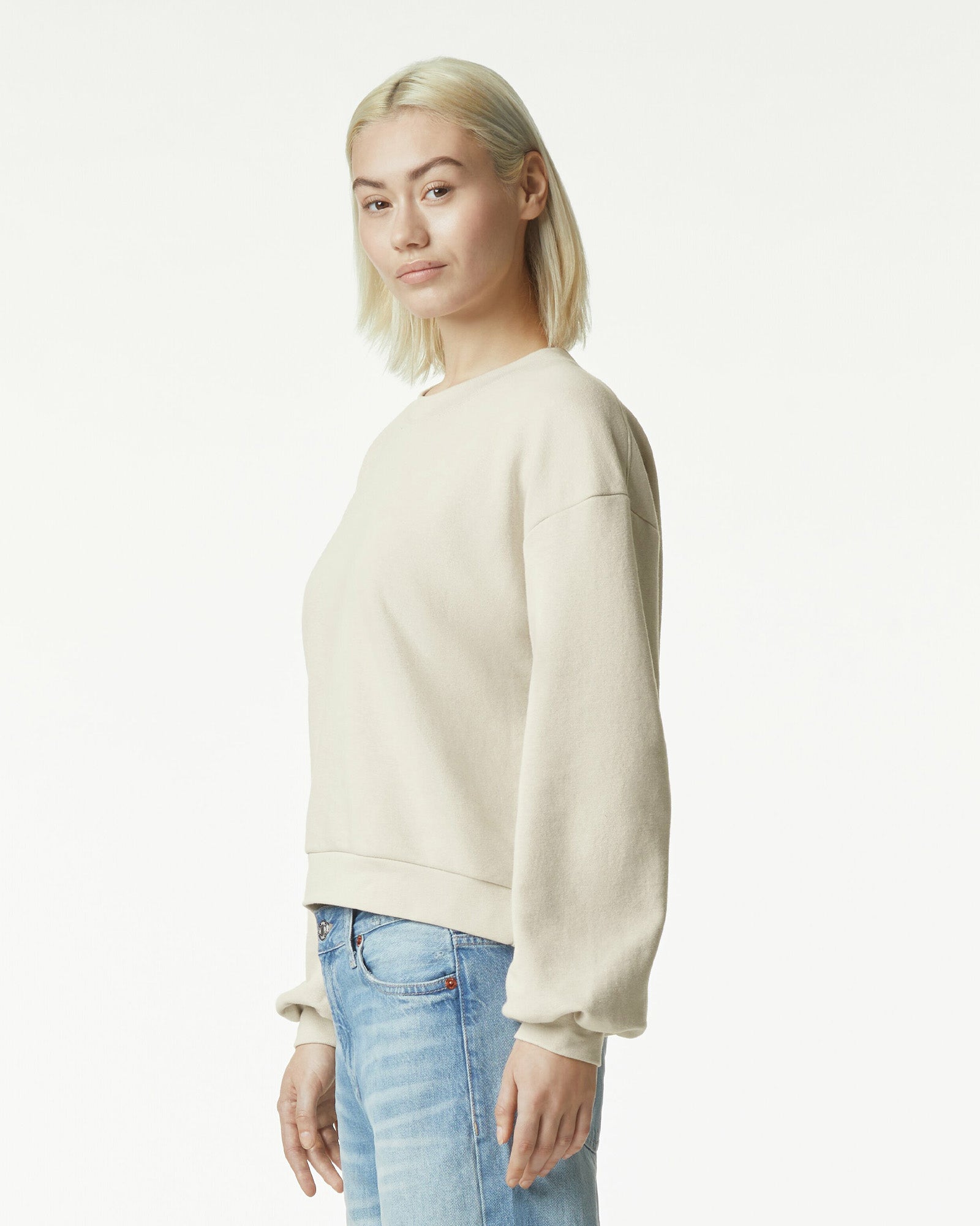 Model wearing a bone colour sweatshirt pairing with blue jeans (side pose) -bone