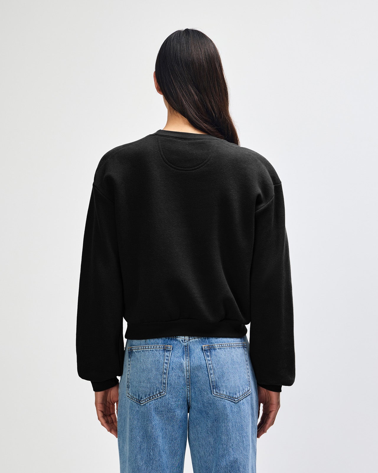 Model wearing a black colour sweatshirt pairing with blue jeans (back pose) -black