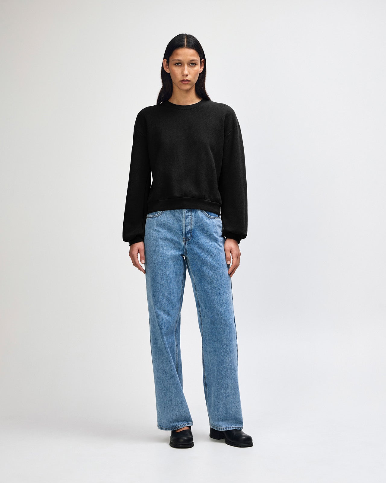 Model wearing a black colour sweatshirt pairing with blue jeans (front pose) -black