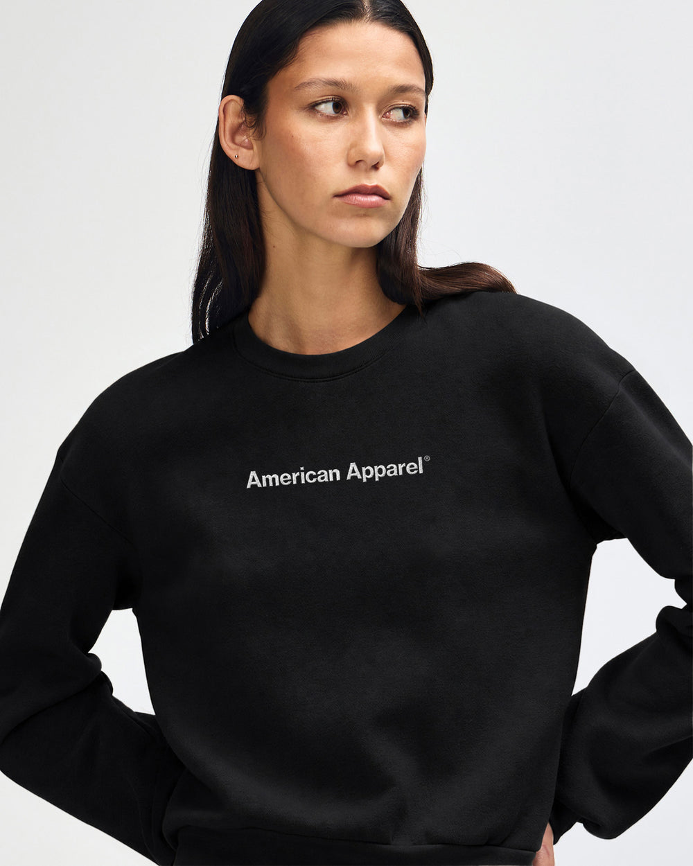 image of Women's Crop Sweatshirt - Embroidered Logo : Person wearing a black American Apparel sweatshirt on a light gray background -black