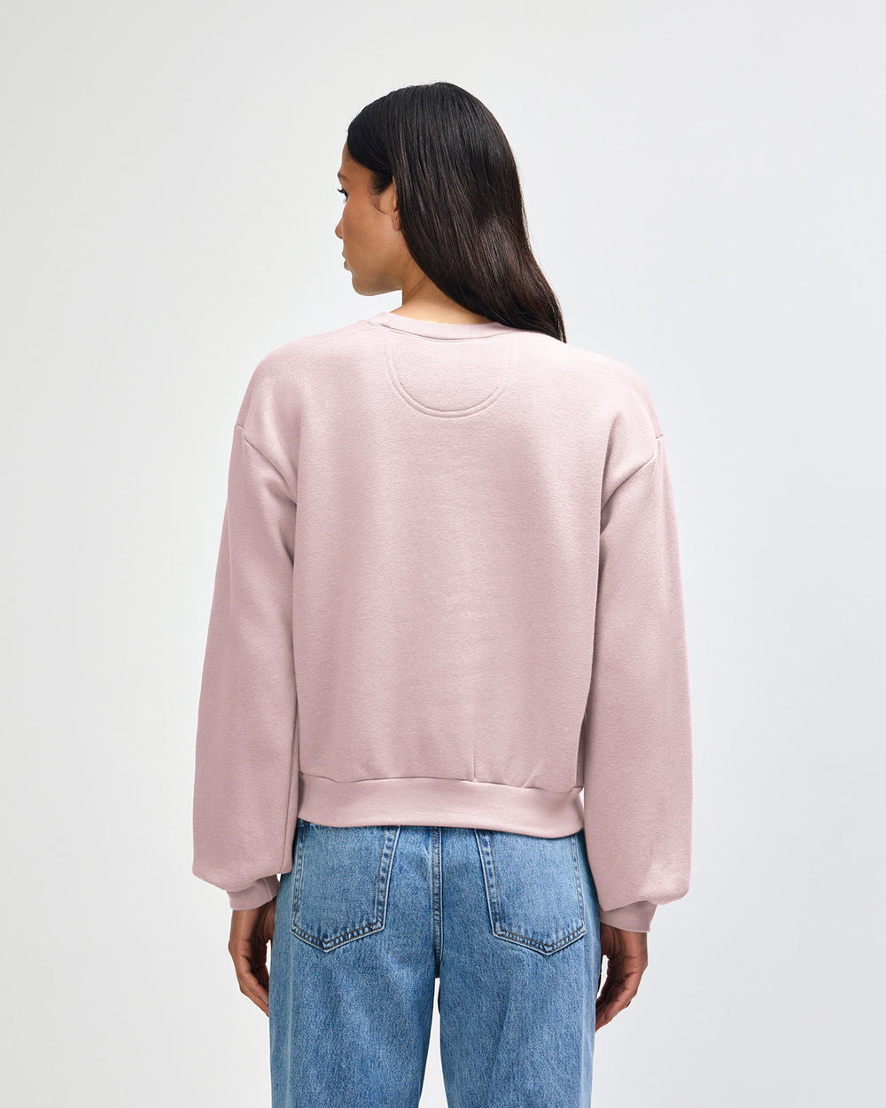 next image of Women's Crop Sweatshirt Tracksuit Set - Embroidered Logo - Blush : Person wearing a light pink sweatshirt and blue jeans on a white background -blush