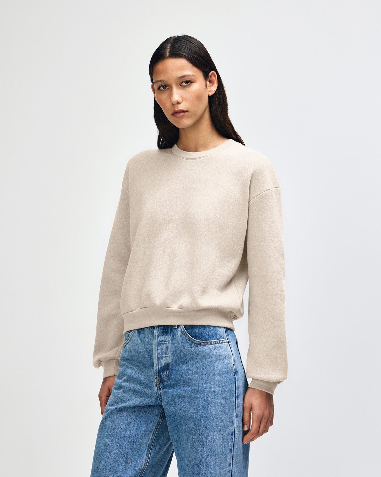 Model wearing a bone colour sweatshirt pairing with blue jeans (front pose) - bone