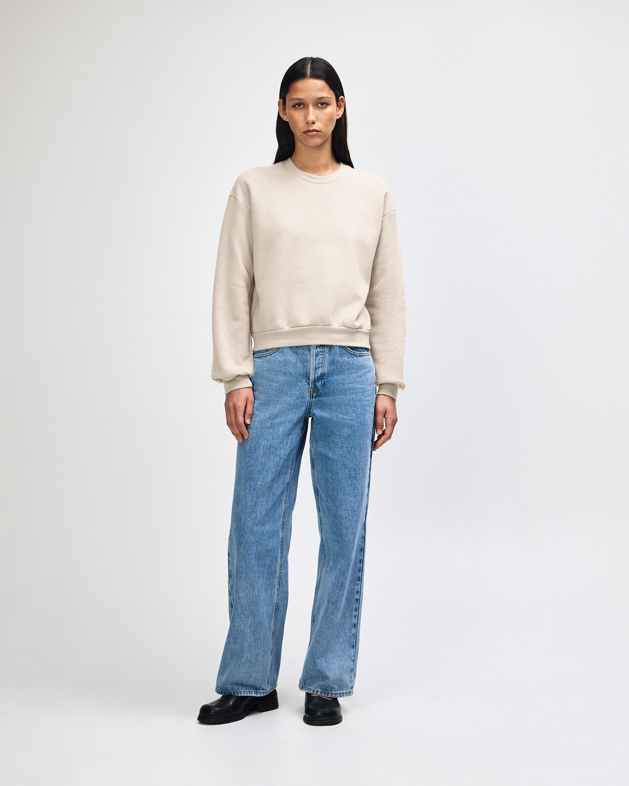 Model wearing a bone colour sweatshirt pairing with blue jeans (front pose) - bone