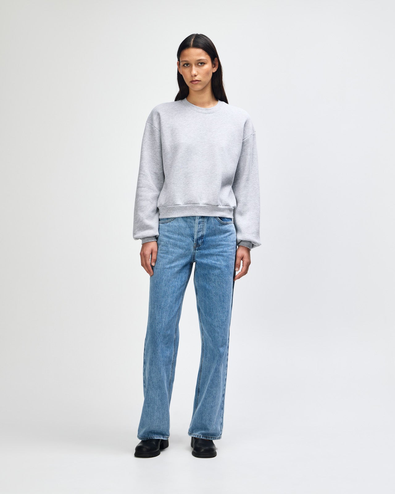 Model wearing a heather grey colour sweatshirt pairing with blue jeans (front pose) -heather grey