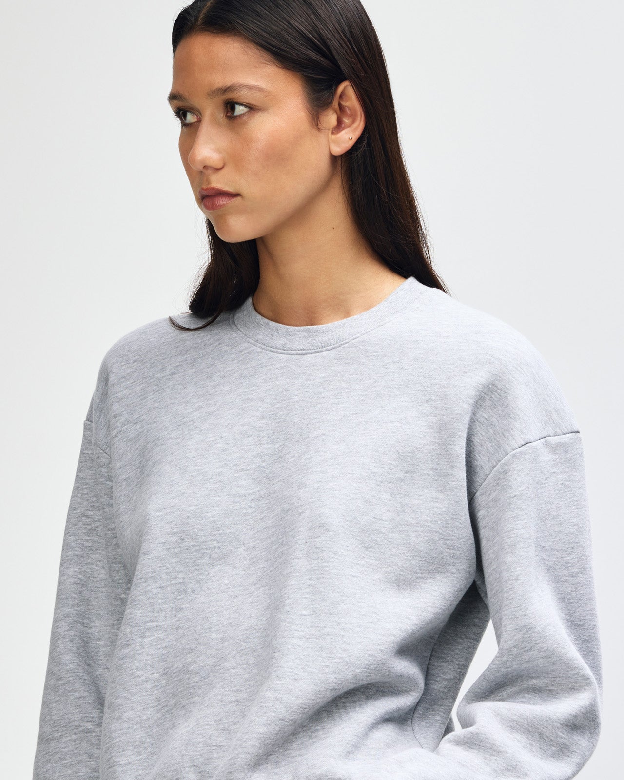 Model wearing a heather grey colour sweatshirt pairing with blue jeans (front pose) -heather grey