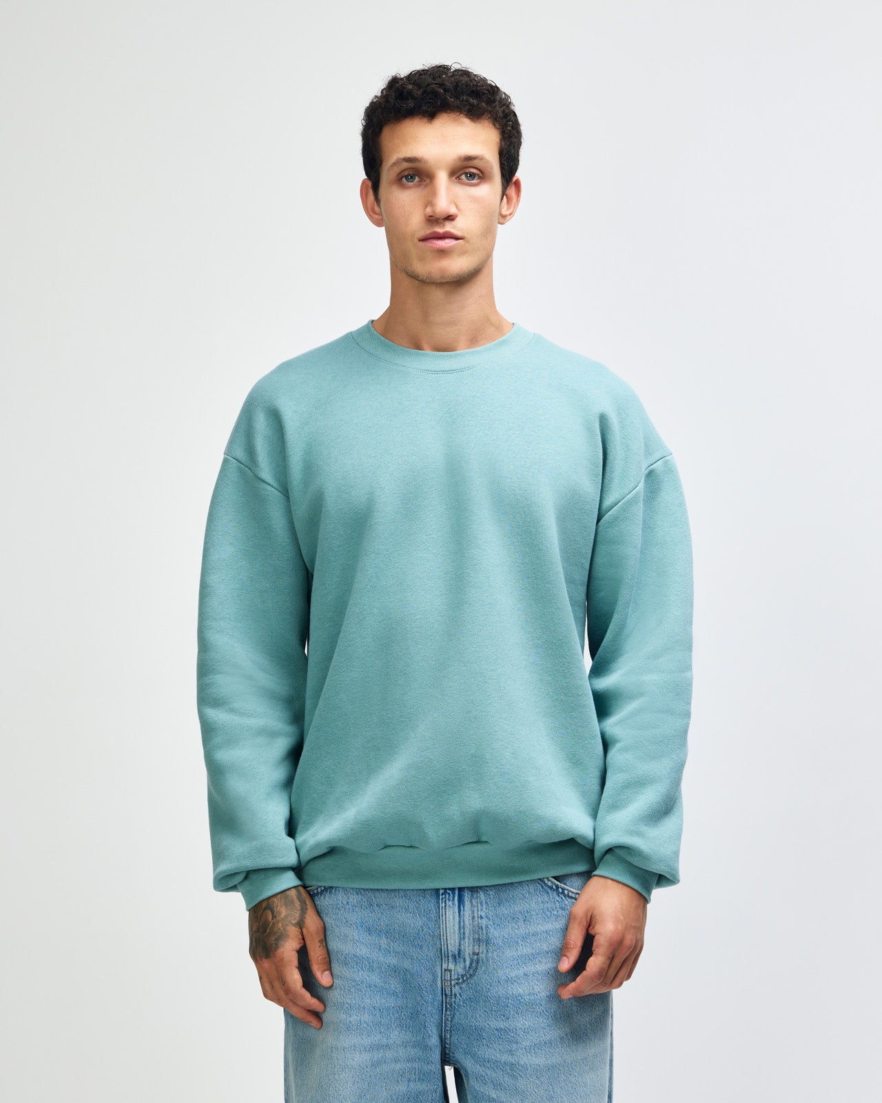 Male model wearing a Reflex Unisex Crewneck Sweatshirt (front pose) -arctic