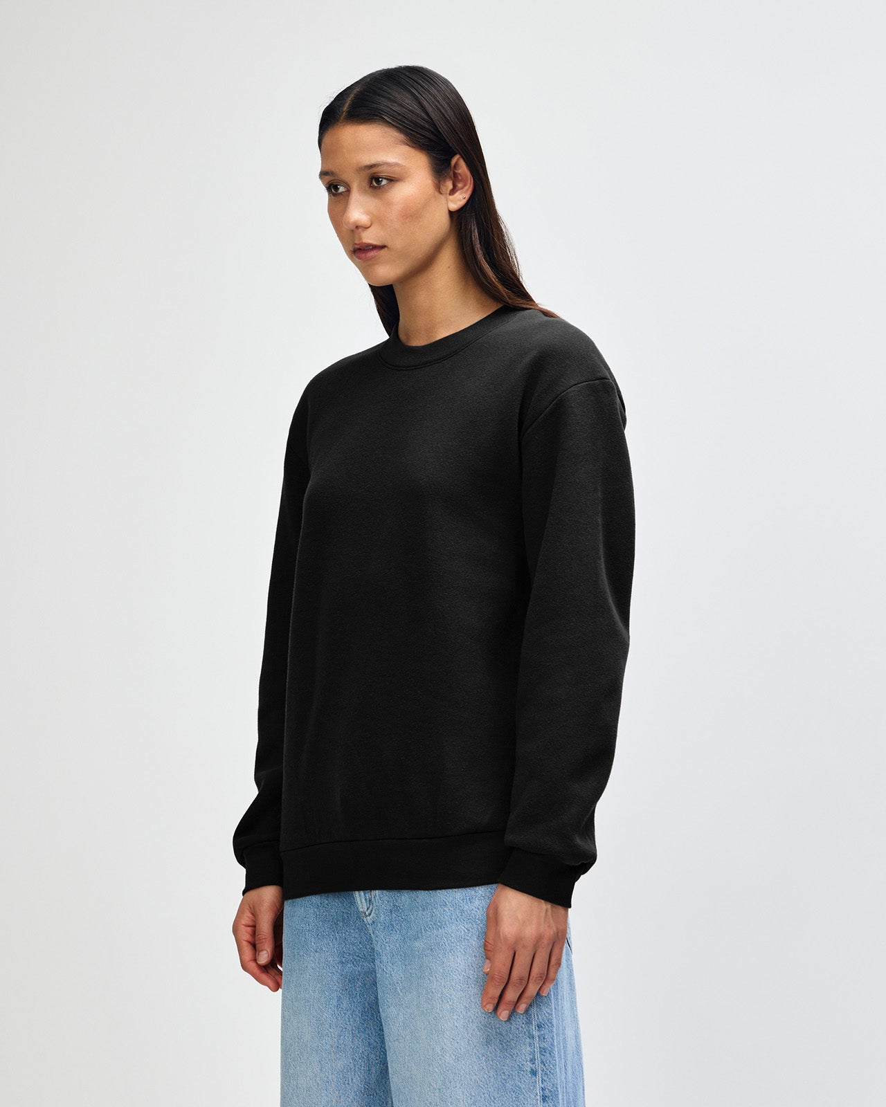 Female model wearing a Reflex Unisex Crewneck Sweatshirt (front pose) -black