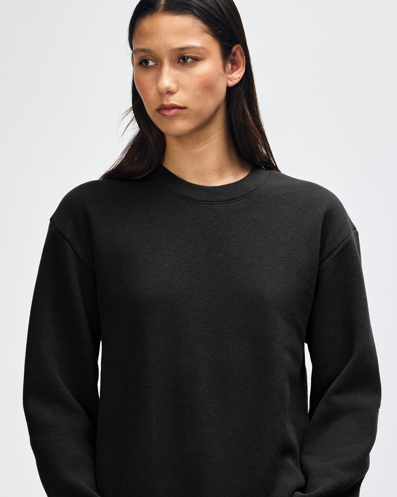 Female model wearing a Reflex Unisex Crewneck Sweatshirt (front pose) -black