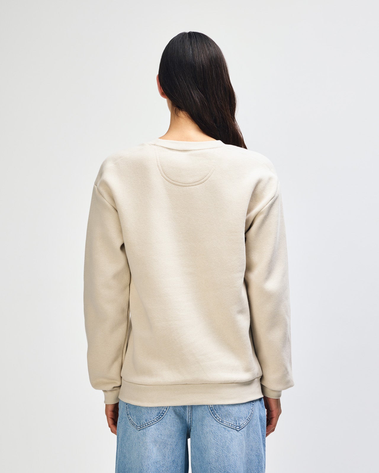 Female model wearing a Reflex Unisex Crewneck Sweatshirt (front pose) -bone