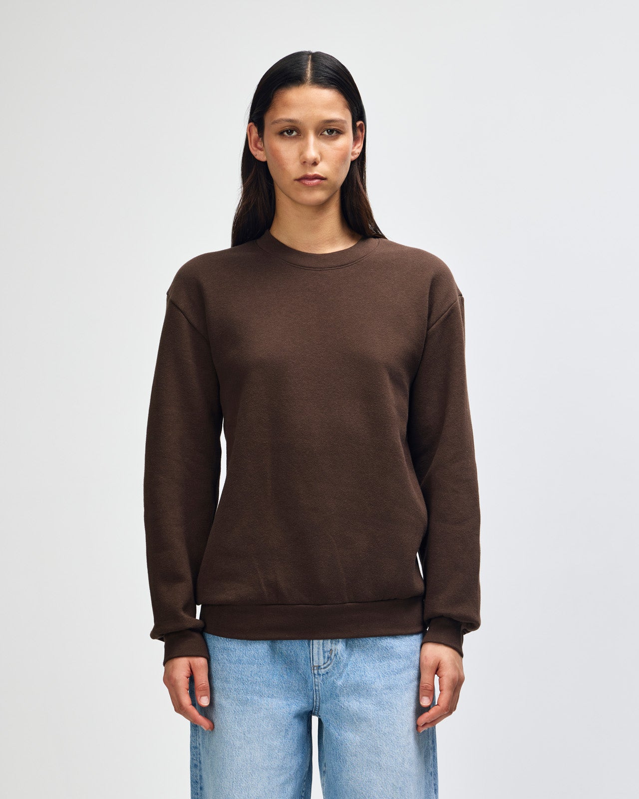Female model wearing a Reflex Unisex Crewneck Sweatshirt (front pose) -brown