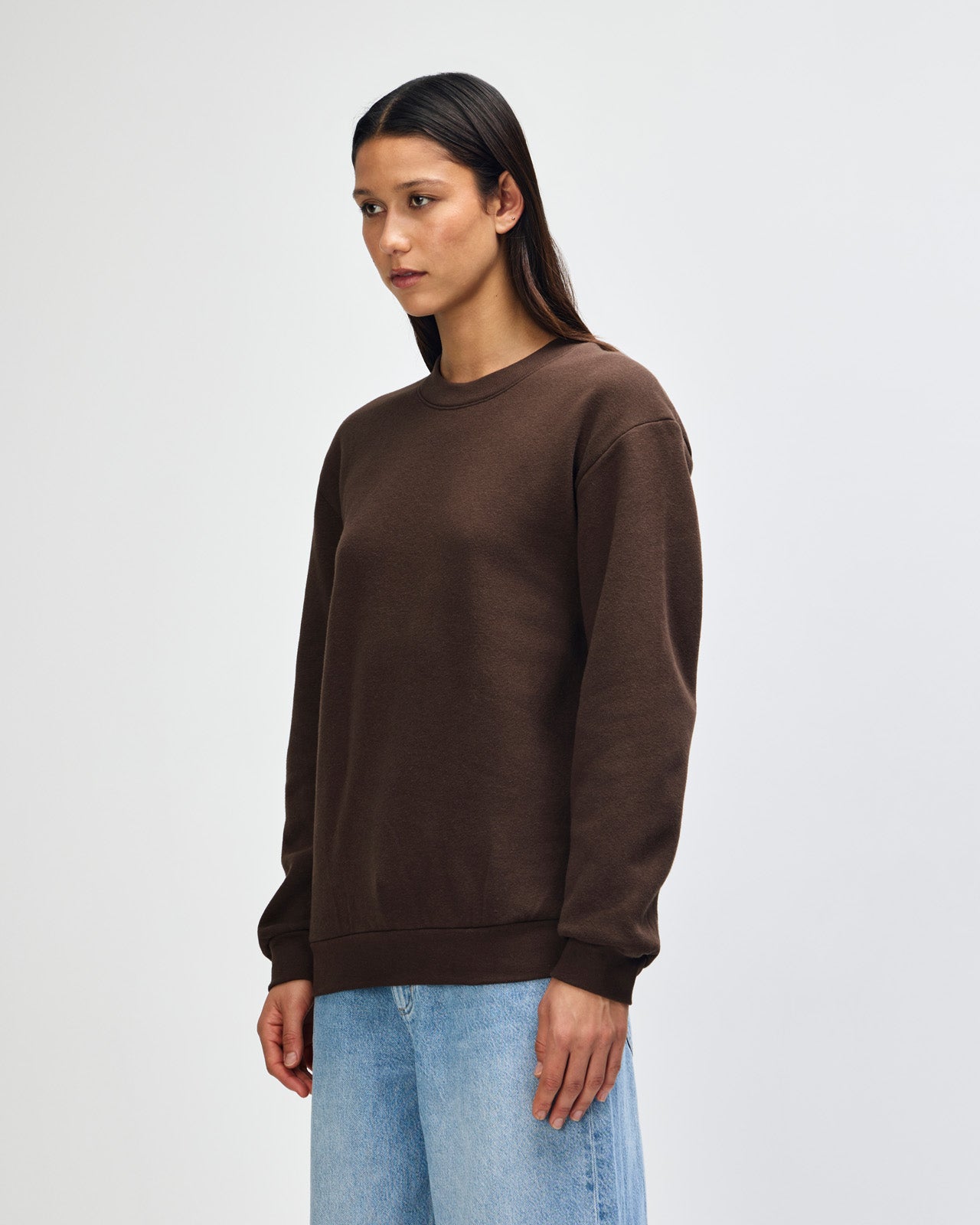 Female model wearing a Reflex Unisex Crewneck Sweatshirt (front pose) -brown