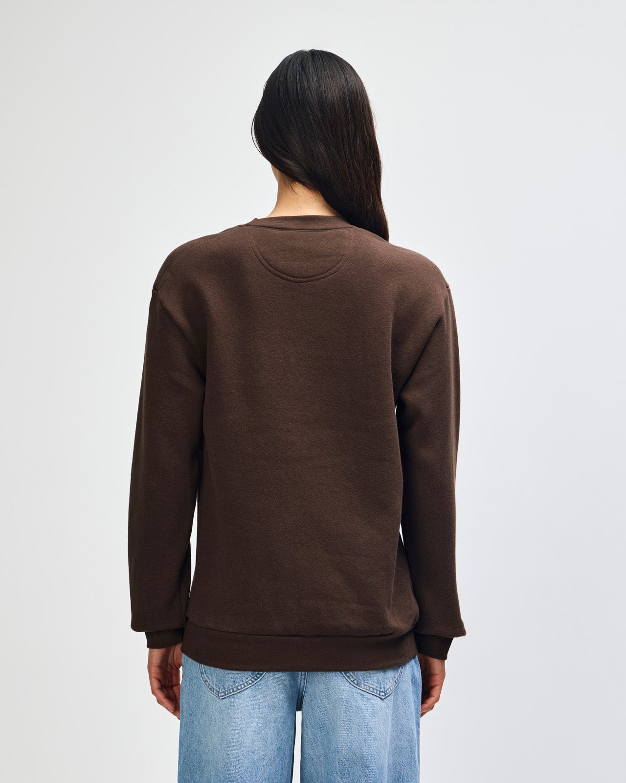 Female model wearing a Reflex Unisex Crewneck Sweatshirt (front pose) -brown