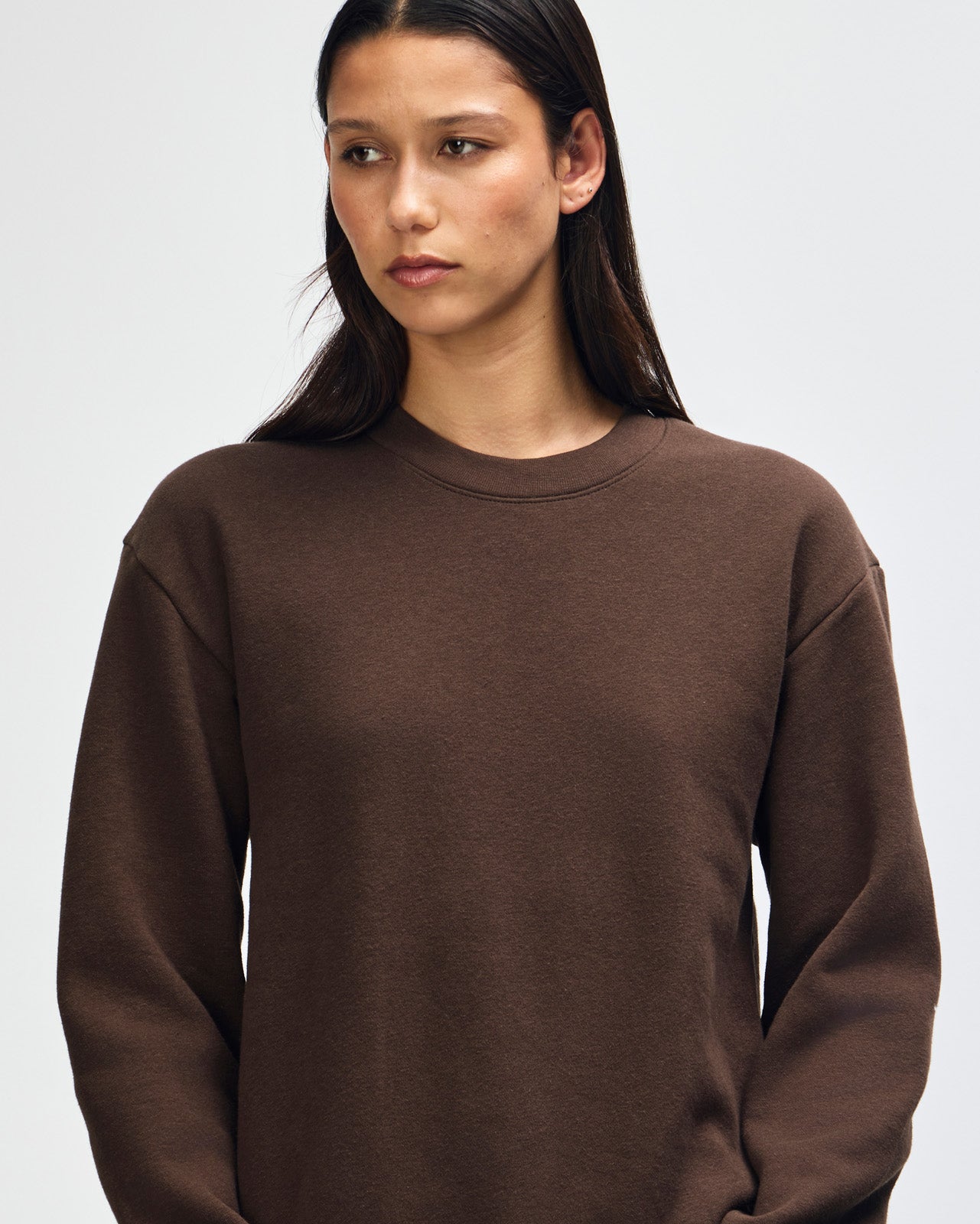 Female model wearing a Reflex Unisex Crewneck Sweatshirt (front pose) -brown