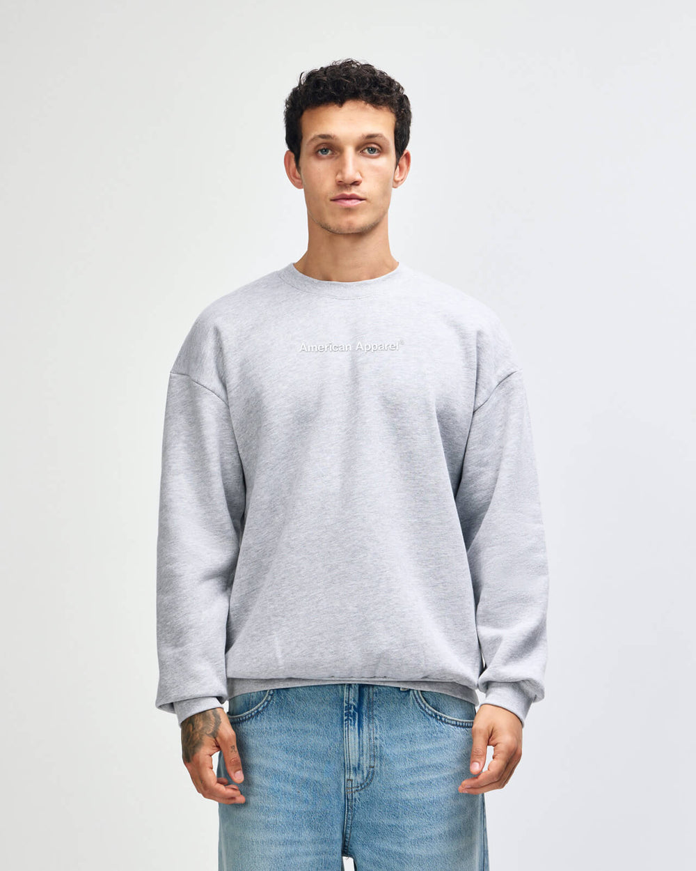image of Crewneck Sweatshirt Tracksuit Set - Embroidered Logo - Heather Grey : Man wearing a gray sweatshirt and blue jeans against a white background -Heather Grey