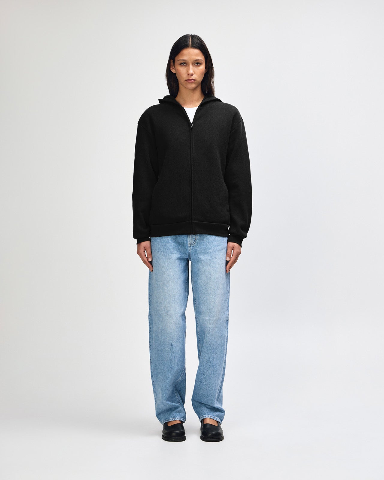 Female model wearing Reflex Unisex Full Zip Hooded Sweatshirt pairing with blue jeans (front pose) -black