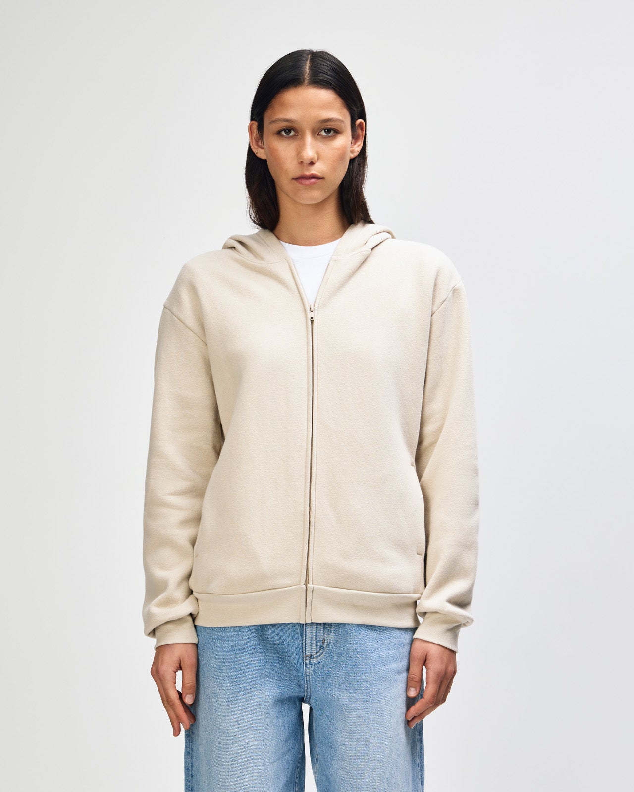 Female model wearing Reflex Unisex Full Zip Hooded Sweatshirt pairing with blue jeans (front pose) -bone