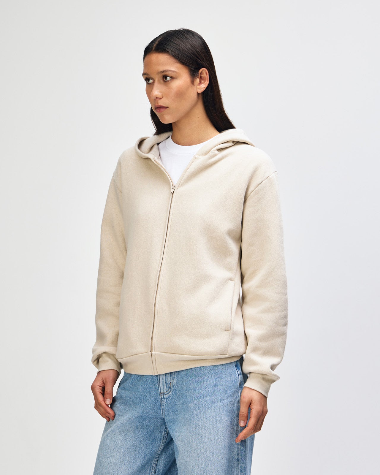 Female model wearing Reflex Unisex Full Zip Hooded Sweatshirt pairing with blue jeans (side pose) -bone