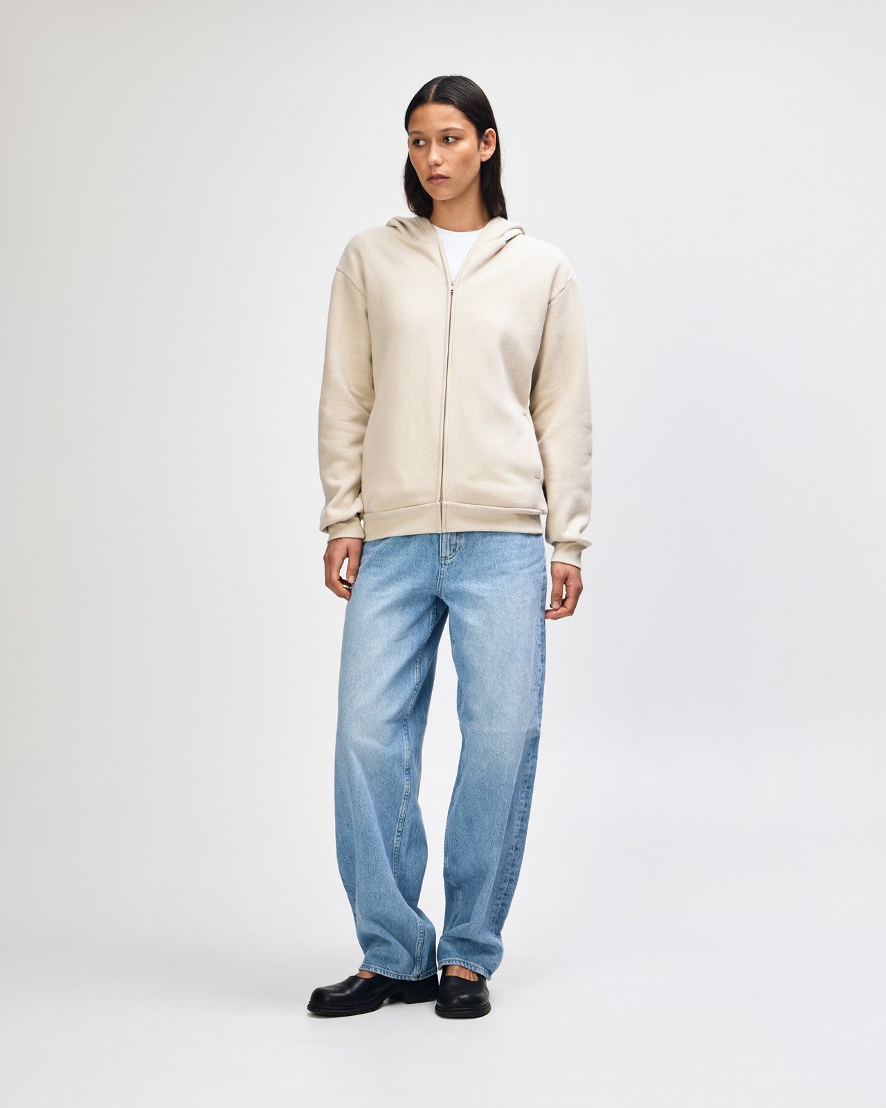 Female model wearing Reflex Unisex Full Zip Hooded Sweatshirt pairing with blue jeans (front pose) -bone