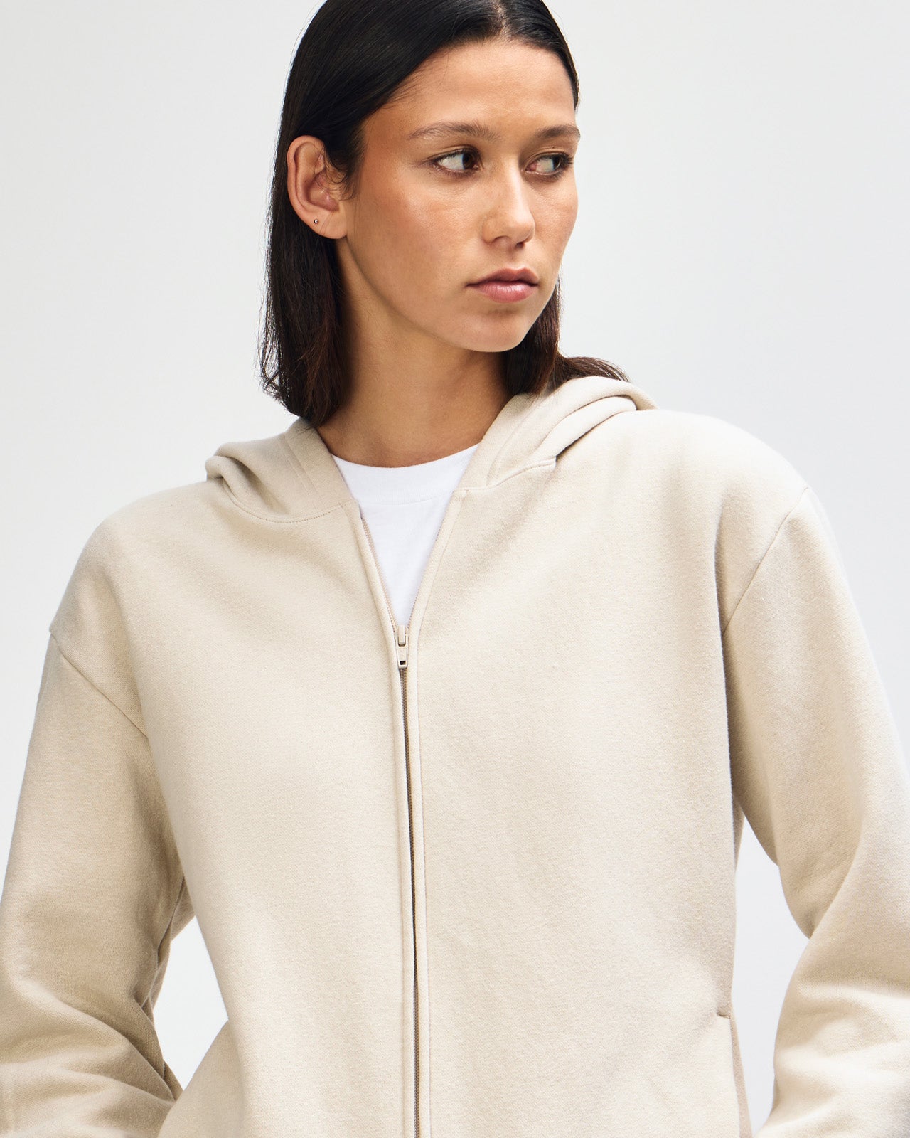 Female model wearing Reflex Unisex Full Zip Hooded Sweatshirt pairing with blue jeans (full pose) -bone