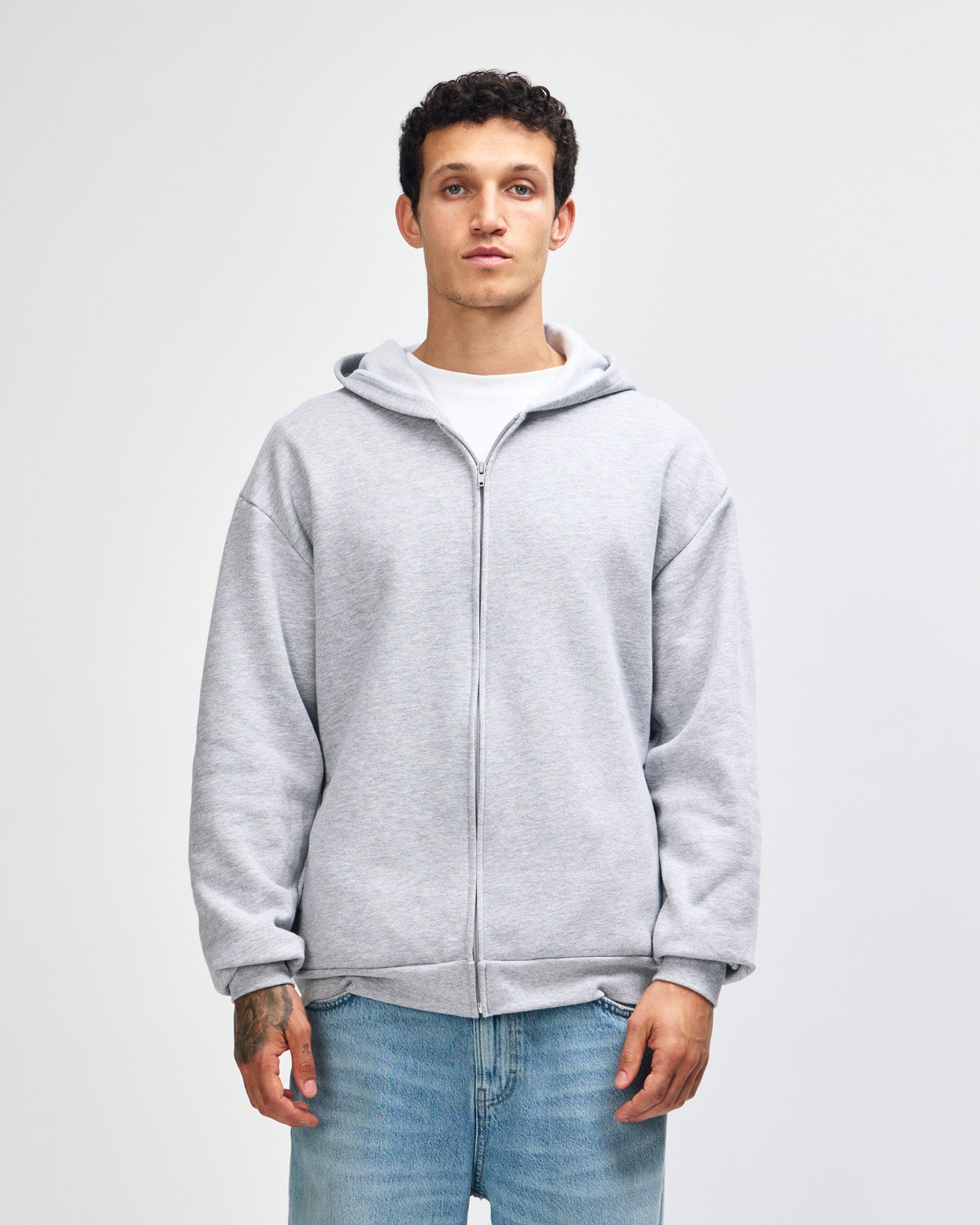 Male model wearing Reflex Unisex Full Zip Hooded Sweatshirt pairing with blue jeans (front pose) -heather grey