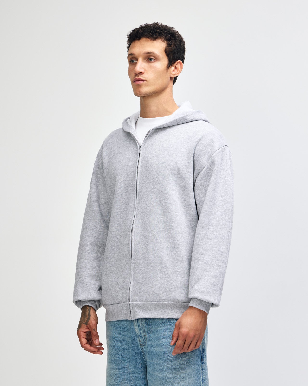 Male model wearing Reflex Unisex Full Zip Hooded Sweatshirt pairing with blue jeans (side pose) -heather grey