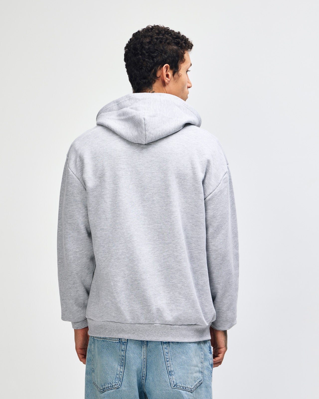 Male model wearing Reflex Unisex Full Zip Hooded Sweatshirt pairing with blue jeans (back pose) -heather grey