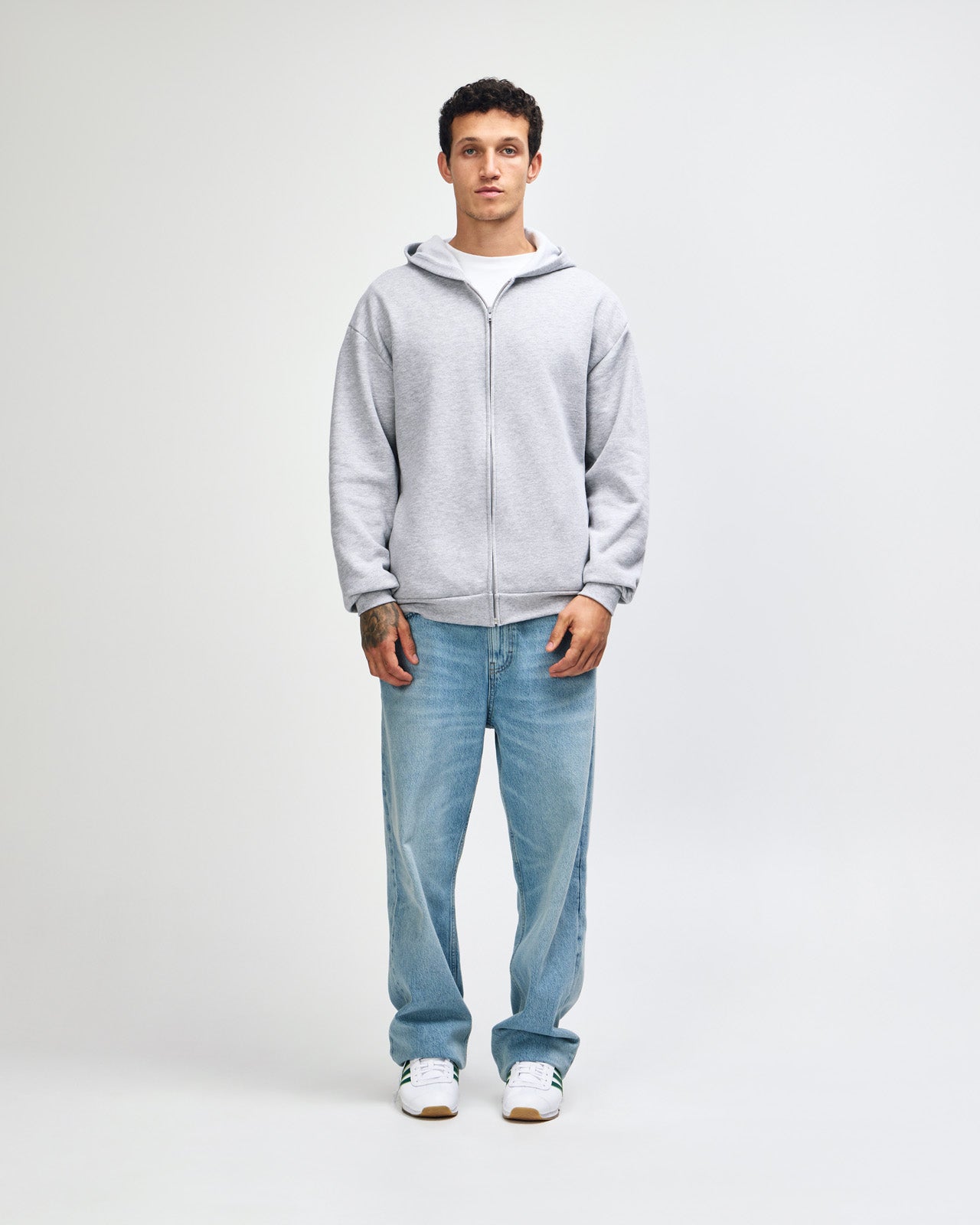 Male model wearing Reflex Unisex Full Zip Hooded Sweatshirt pairing with blue jeans (full view pose) -heather grey