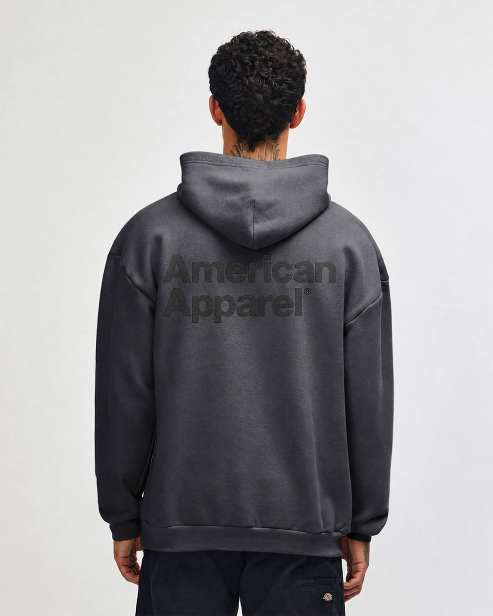 next image of Pullover Hoodie  - Puff Logo : Person wearing a gray hoodie with 'American Apparel' logo on the back against a white background -Asphalt