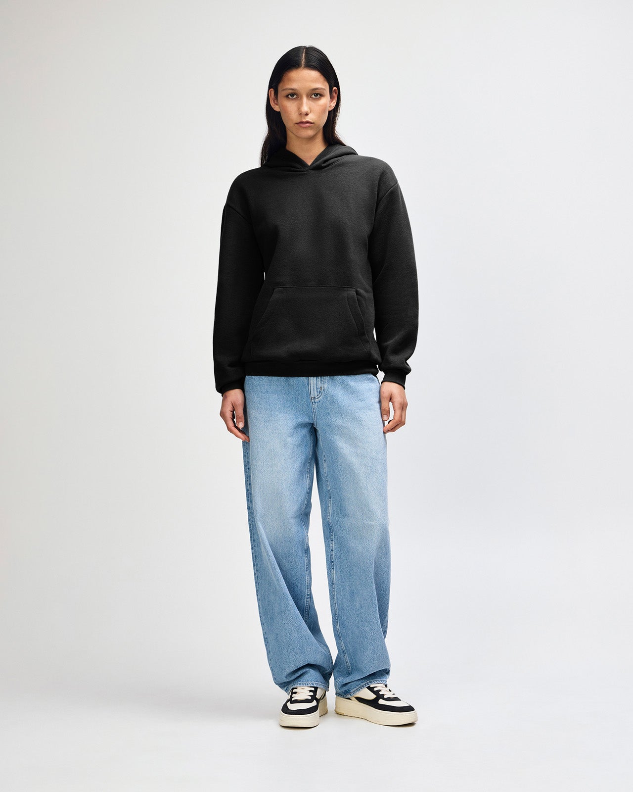 Female model wearing a Reflex Unisex Hooded Sweatshirt (front pose) -black