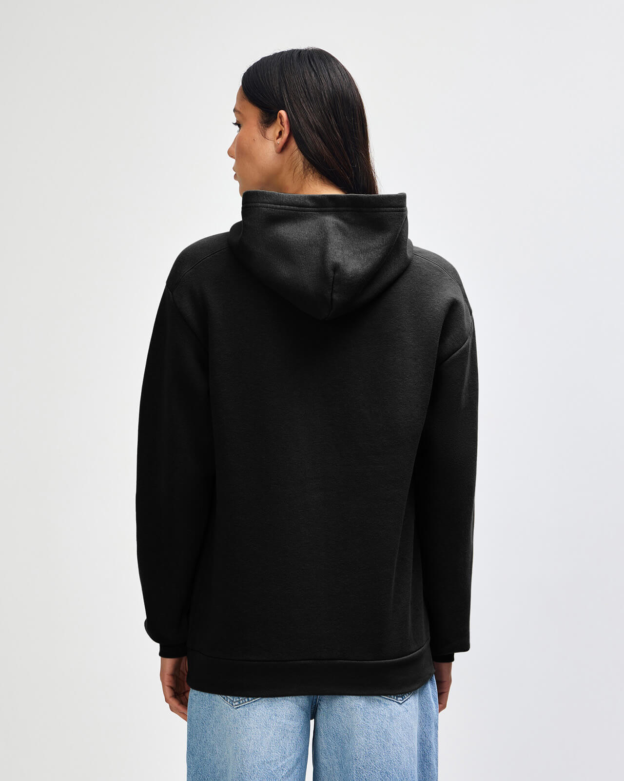 Person wearing a black hoodie from behind on a light gray background -black