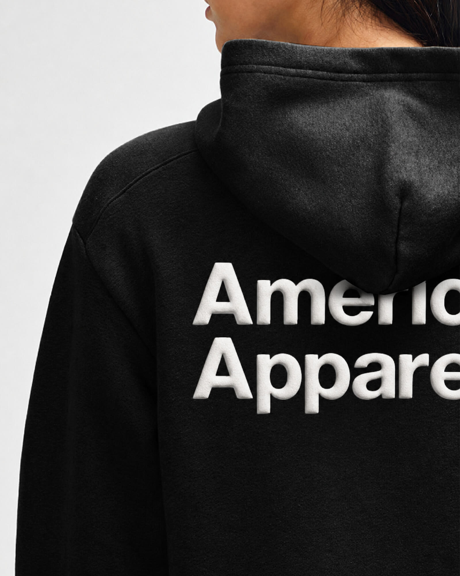 Black hoodie with 'American Apparel' logo on the back against a light gray background -black