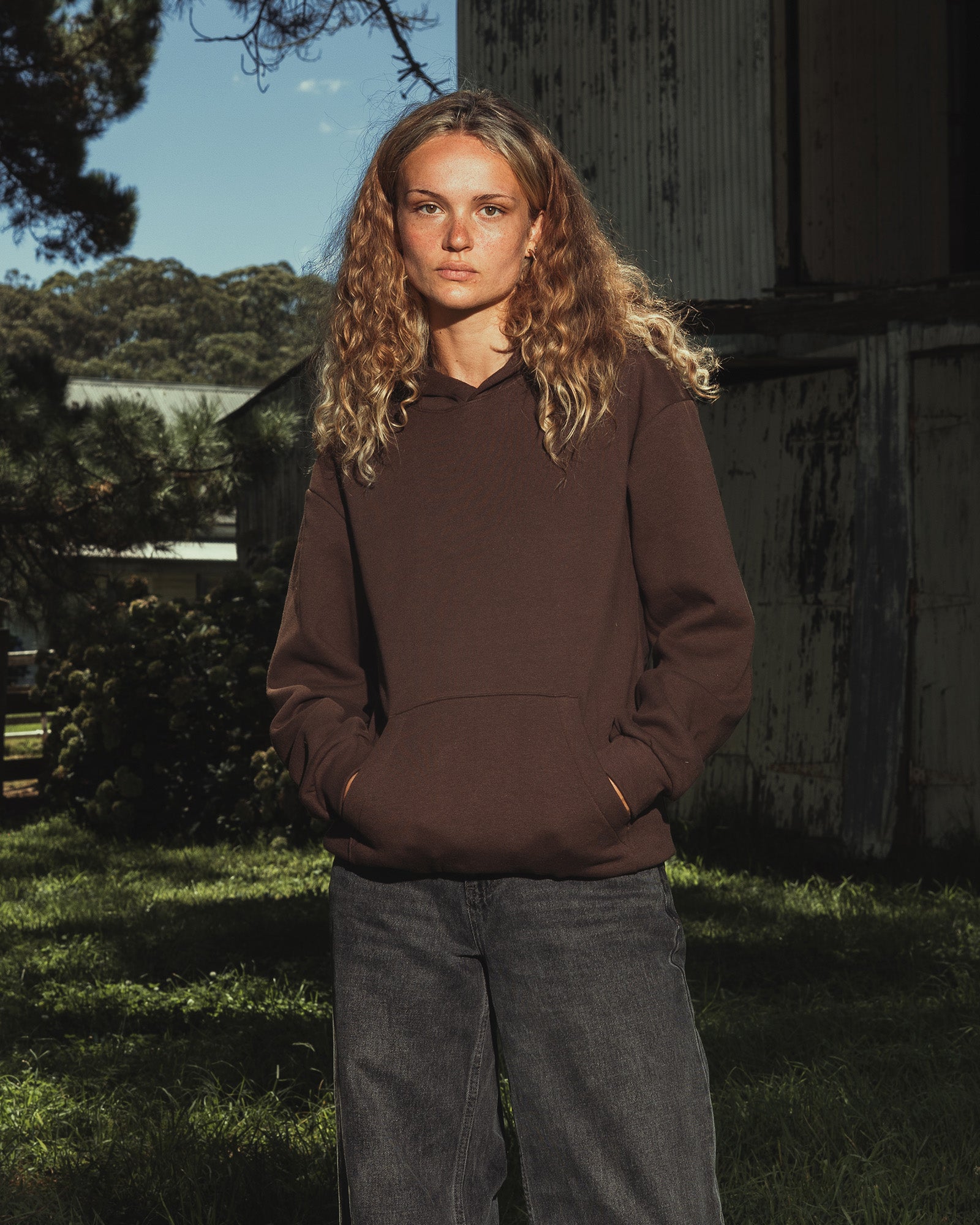 Male model wearing a Reflex Unisex Hooded Sweatshirt (front pose) -brown