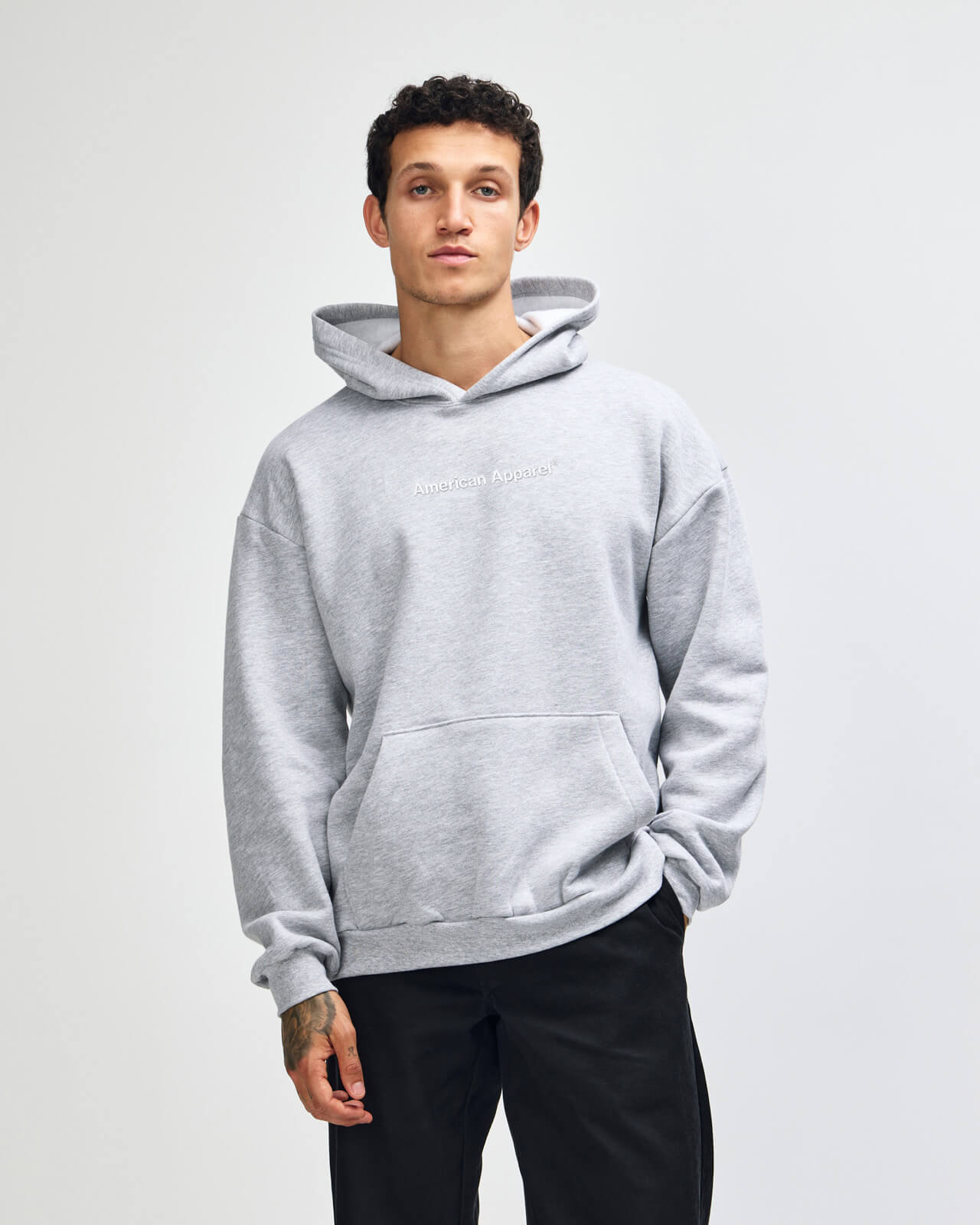Man wearing a gray hoodie on a plain background -Heather Grey