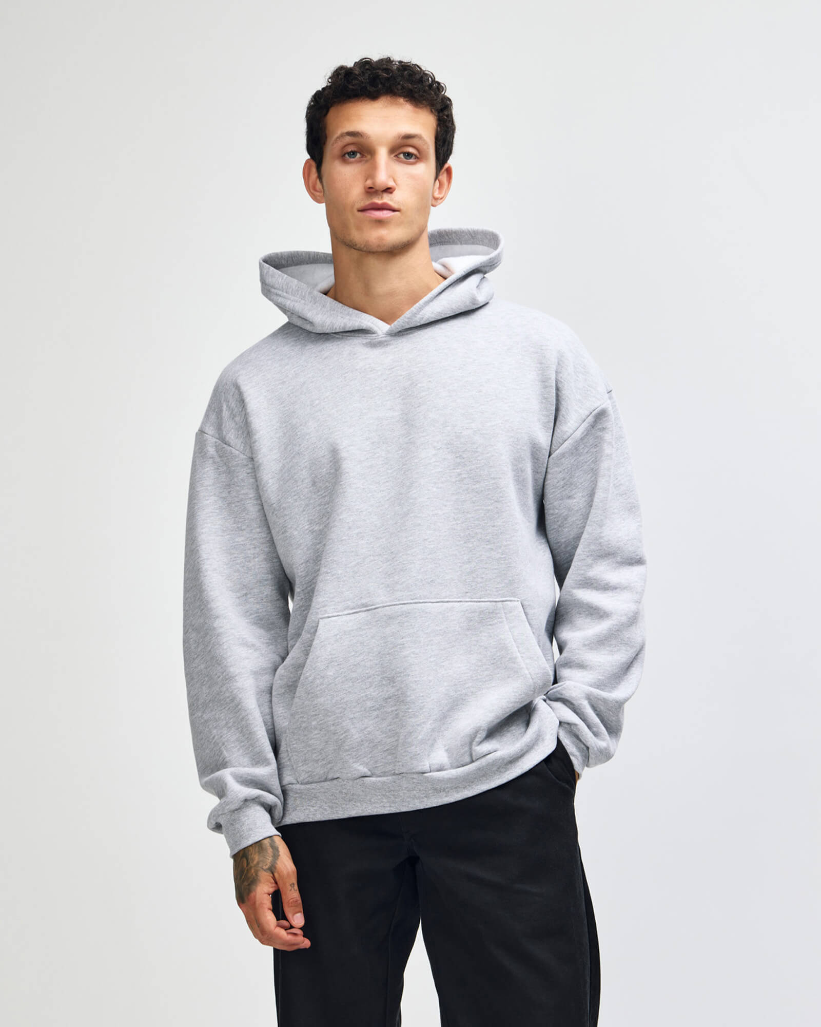 Person wearing a gray hoodie on a plain background -Heather Grey